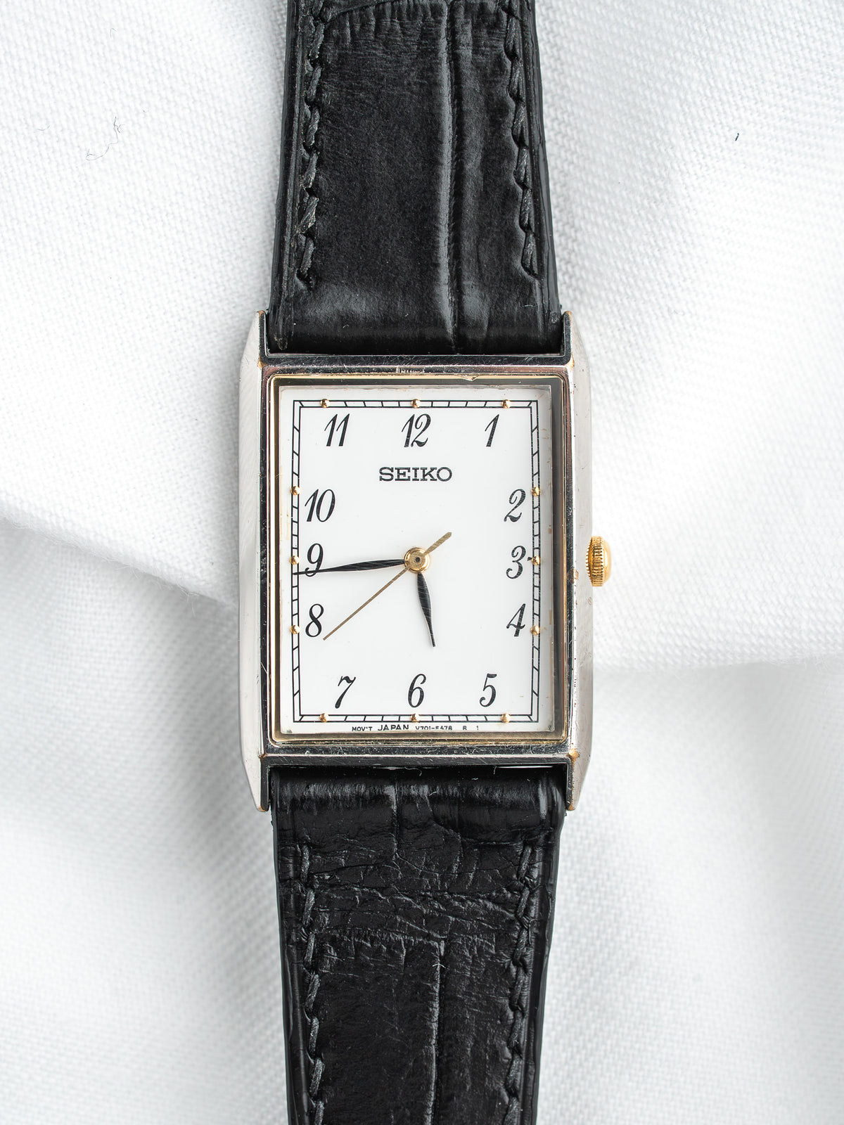 Seiko montre vintage avec cadran blanc, bracelet en cuir noir et accents dorés