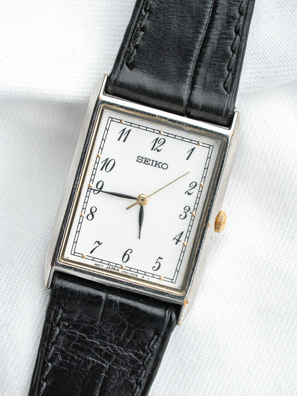 Seiko montre vintage avec cadran blanc, bracelet en cuir noir et boîtier rectangulaire