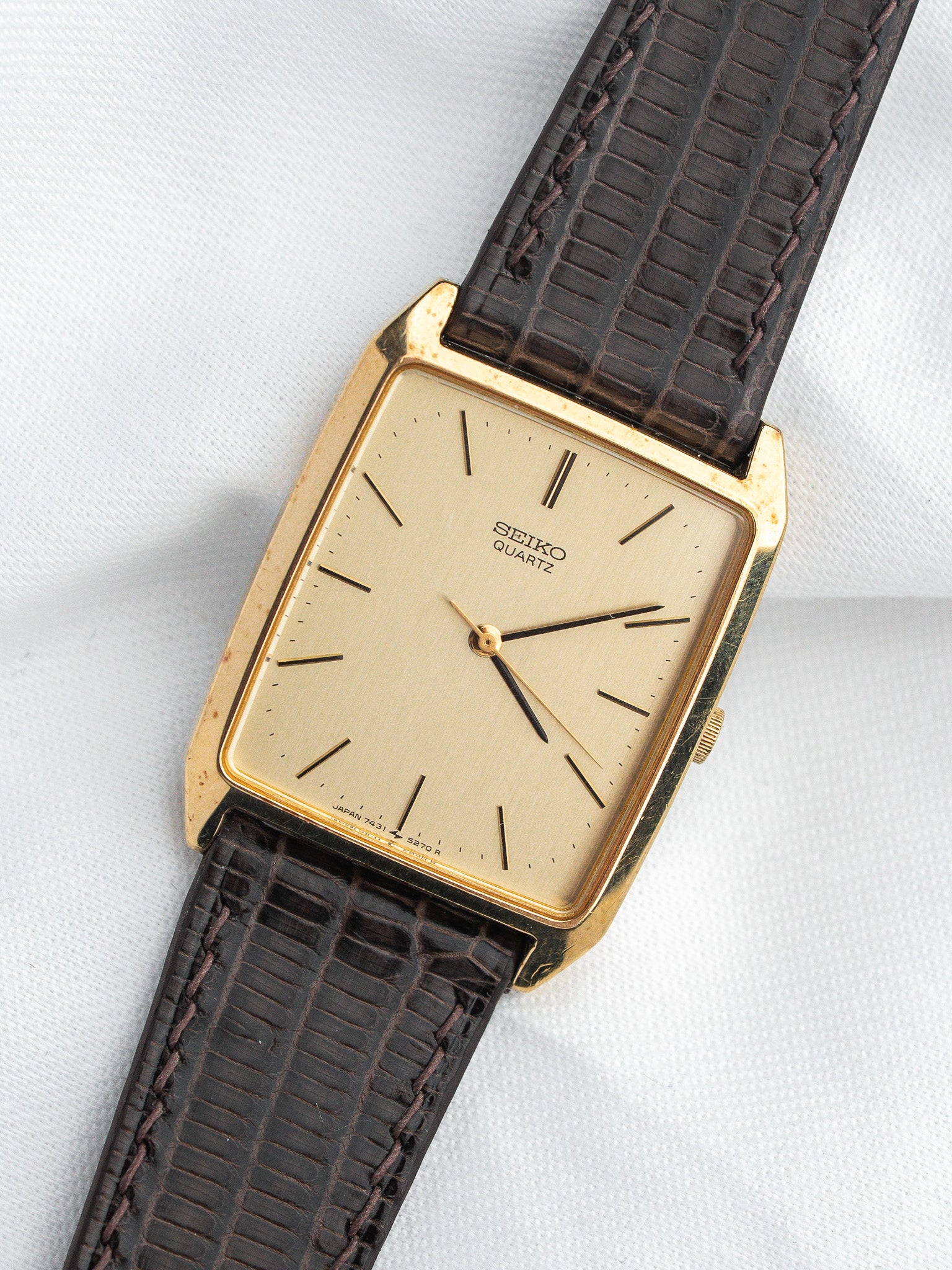 Vintage Seiko Quartz watch with gold case, cream dial, and brown textured leather strap