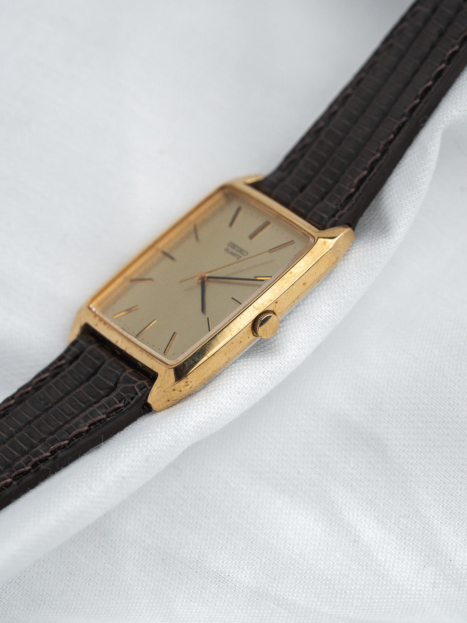 Vintage Seiko watch with gold case, cream dial, and brown leather strap