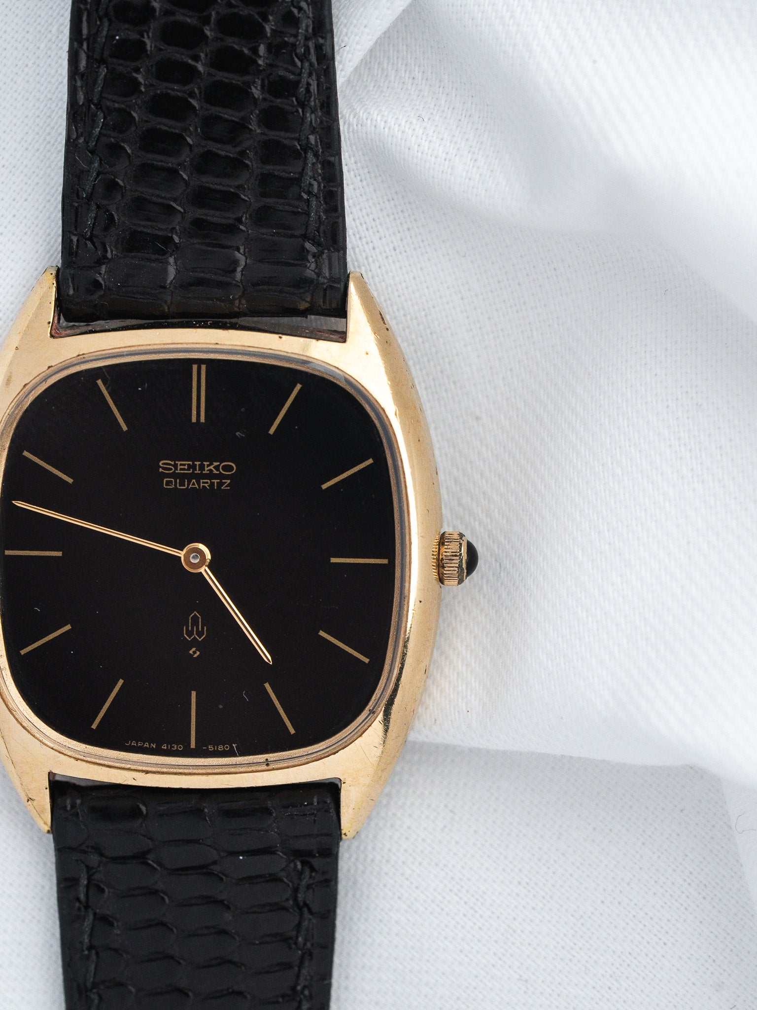 Seiko Quartz vintage watch with gold case, black dial, and textured black strap