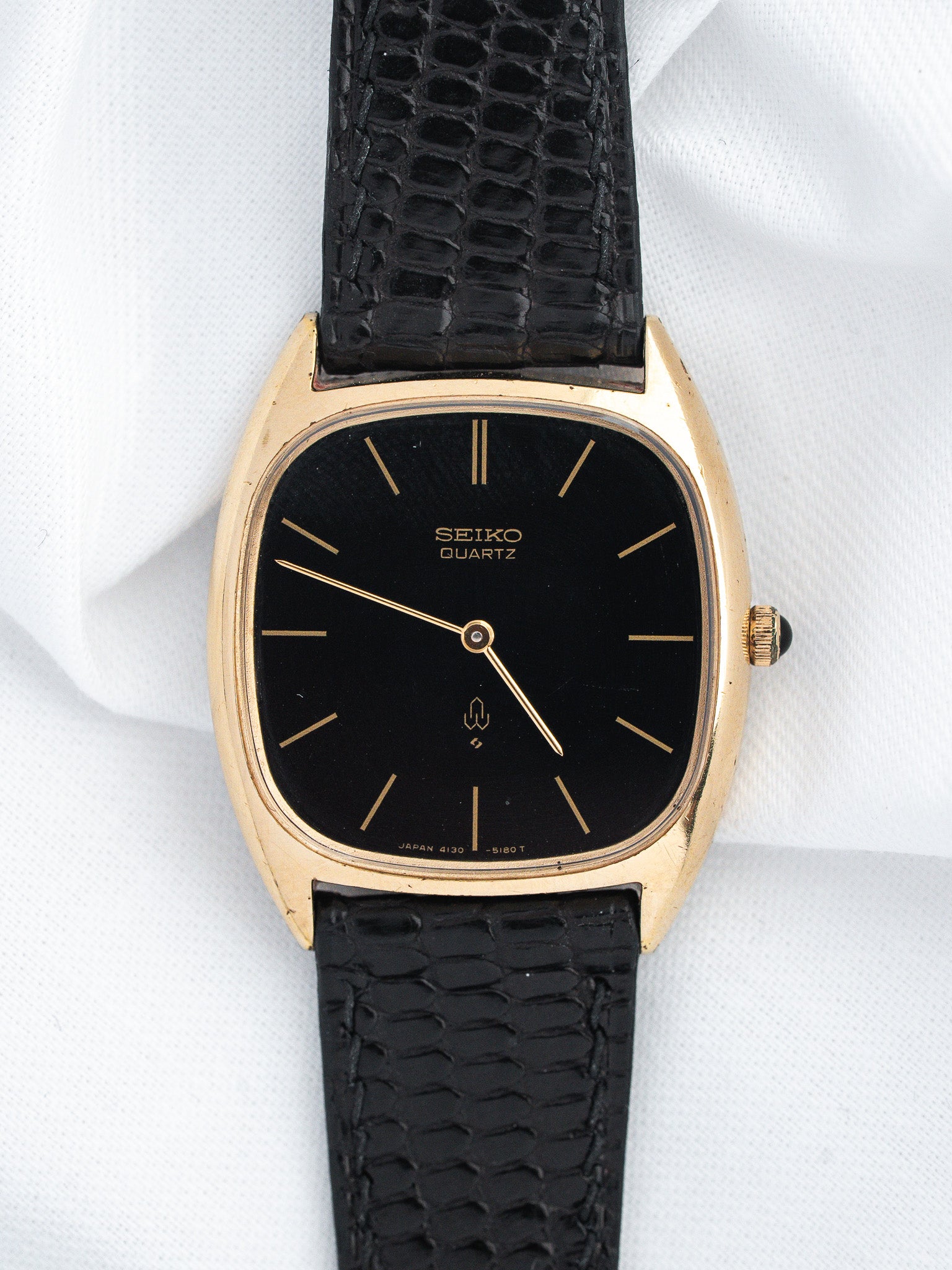 Seiko Quartz vintage watch with gold case, black dial, and textured strap
