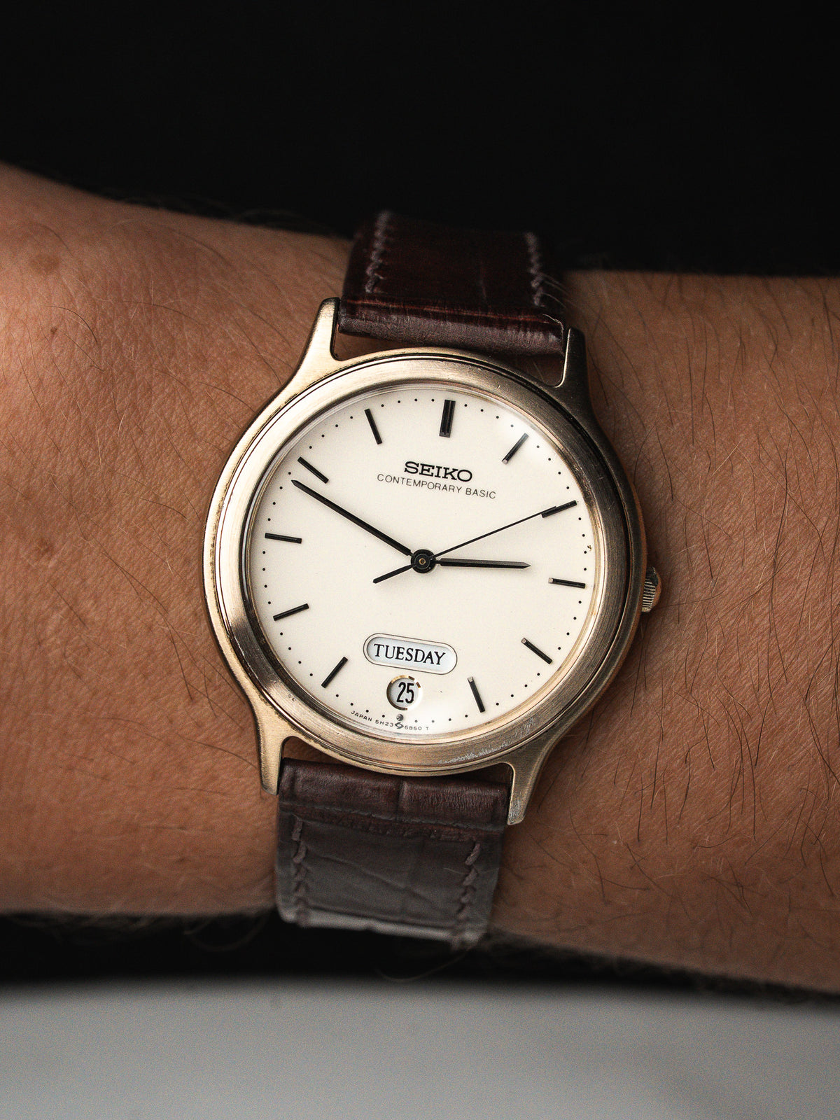 Montre Seiko avec cadran blanc, boîtier doré et bracelet en cuir marron vintage.