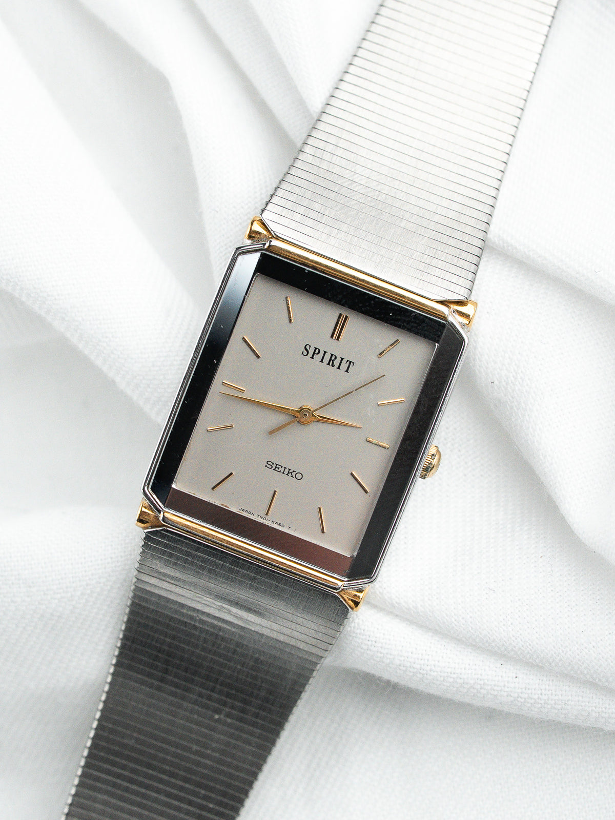 Montre Seiko Spirit vintage au cadran rectangulaire beige et bracelet en acier argenté.