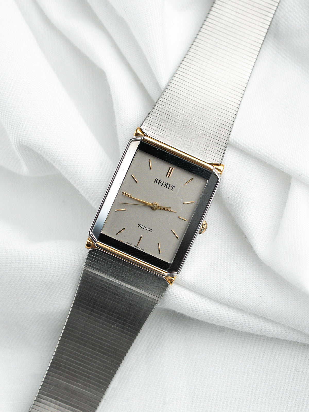Montre Seiko Spirit vintage rectangulaire avec cadran gris et bracelet en maille argentée.