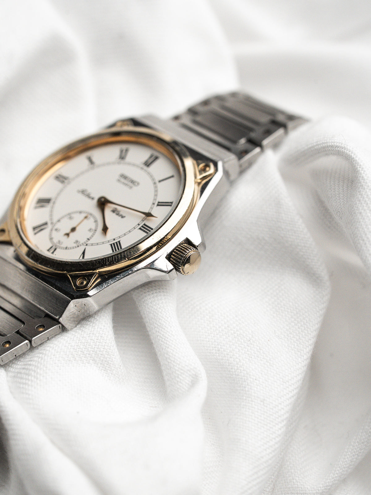 Vintage Seiko Watch in steel and gold, white dial, placed on a white fabric