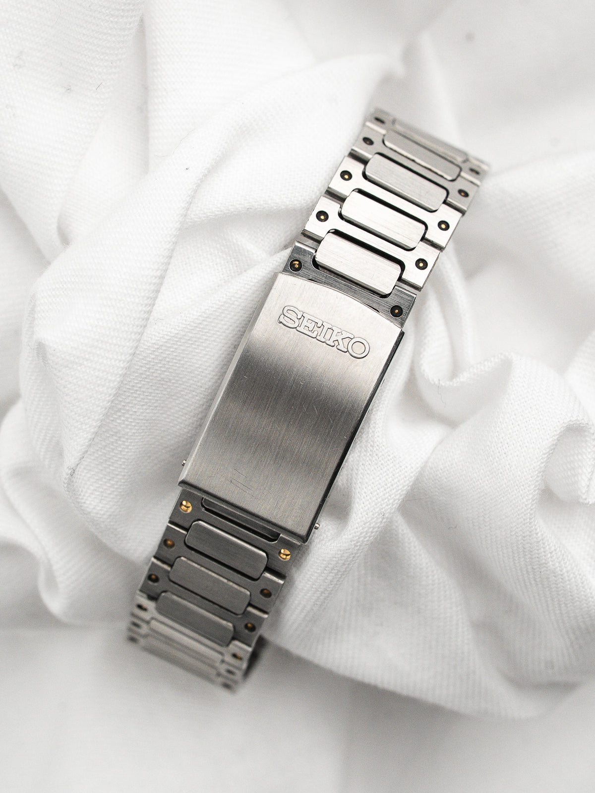 Vintage watch strap Seiko in stainless steel placed on a white fabric