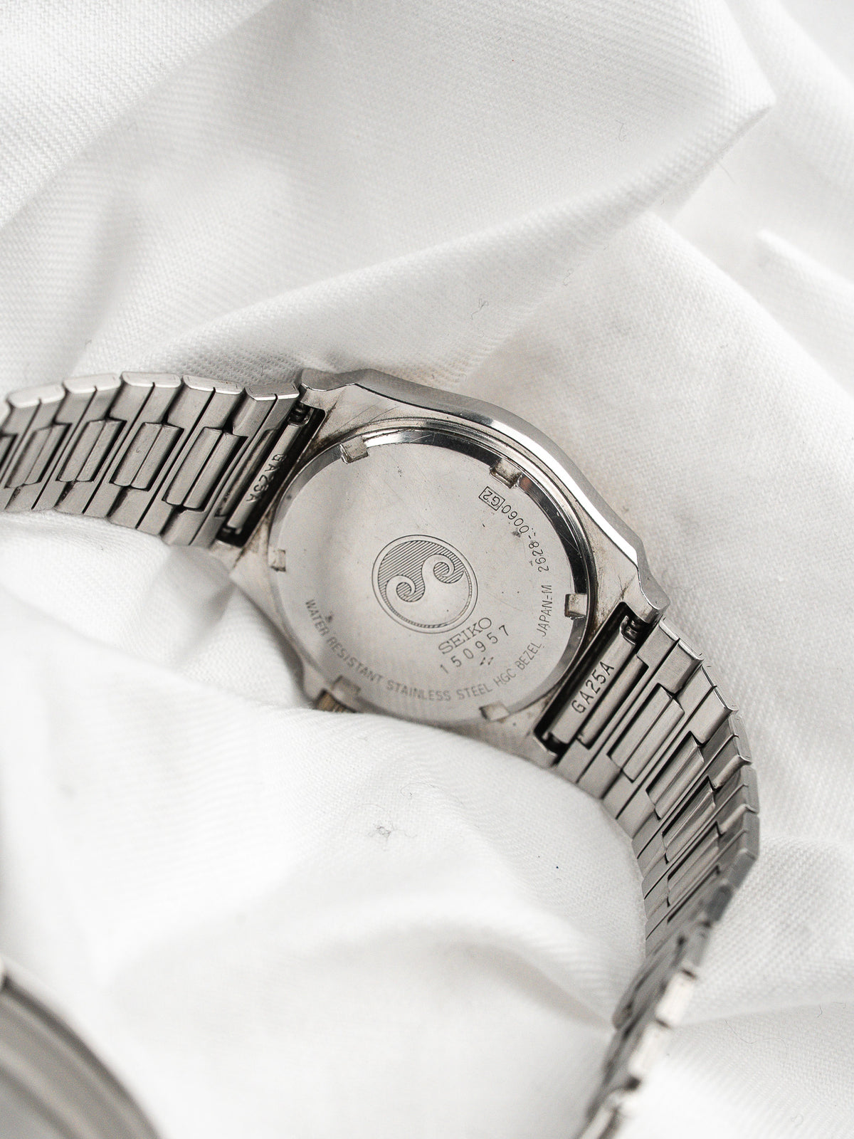 Back of a vintage Seiko watch in stainless steel on a white fabric background