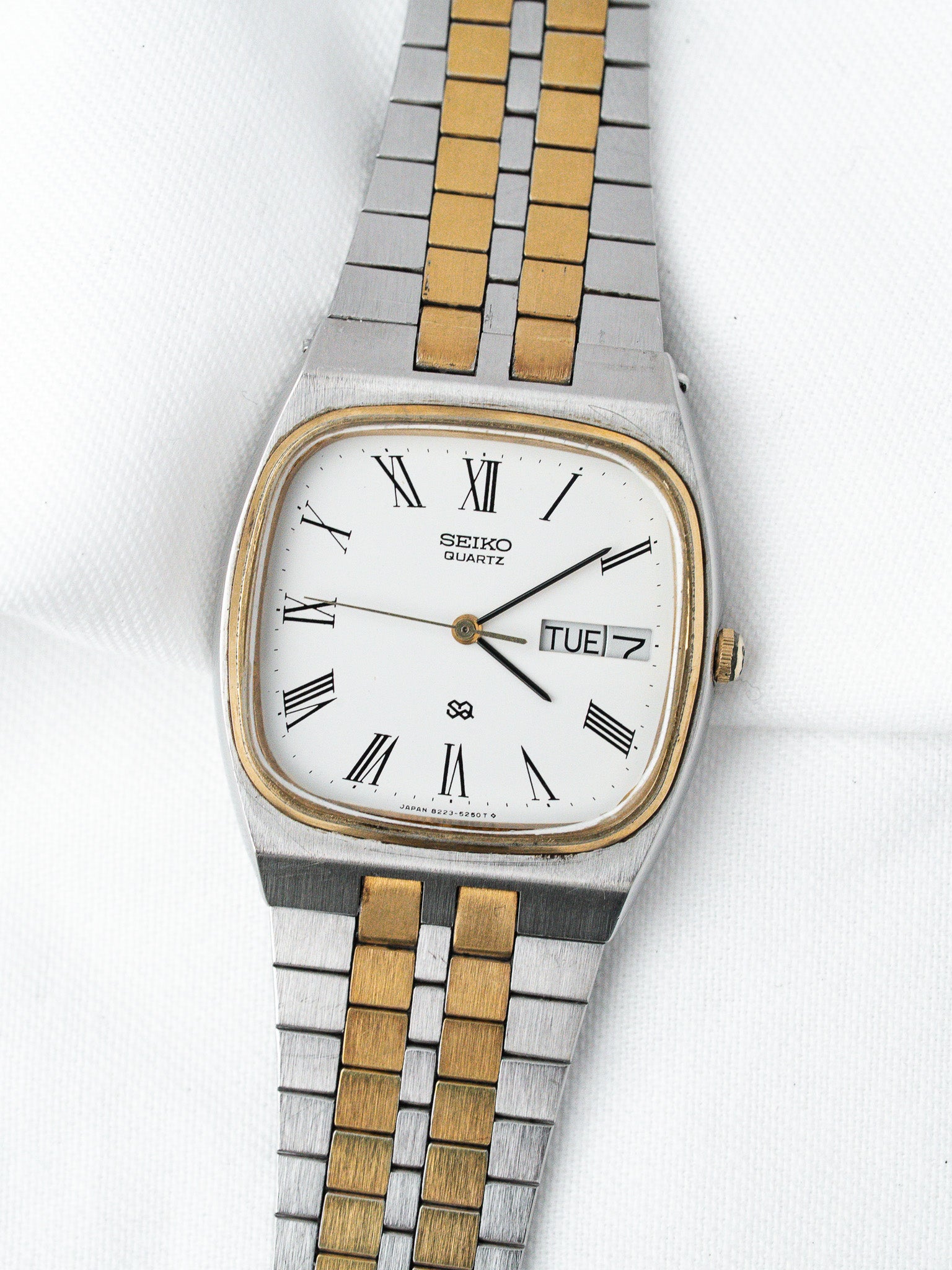 Seiko Quartz vintage watch with white dial, Roman numerals, two-tone bracelet on white background