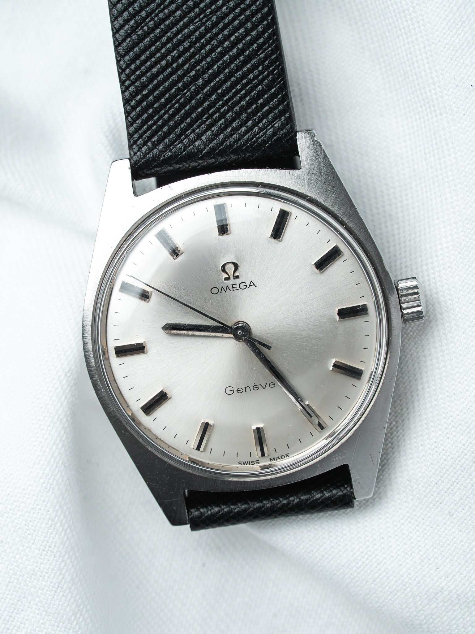 Omega Genève vintage watch with silver dial, black strap, and steel case