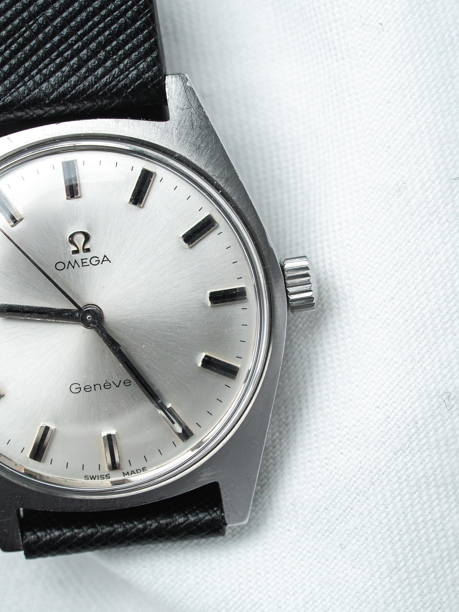 Omega Genève vintage watch with silver dial, black markers, and black leather strap