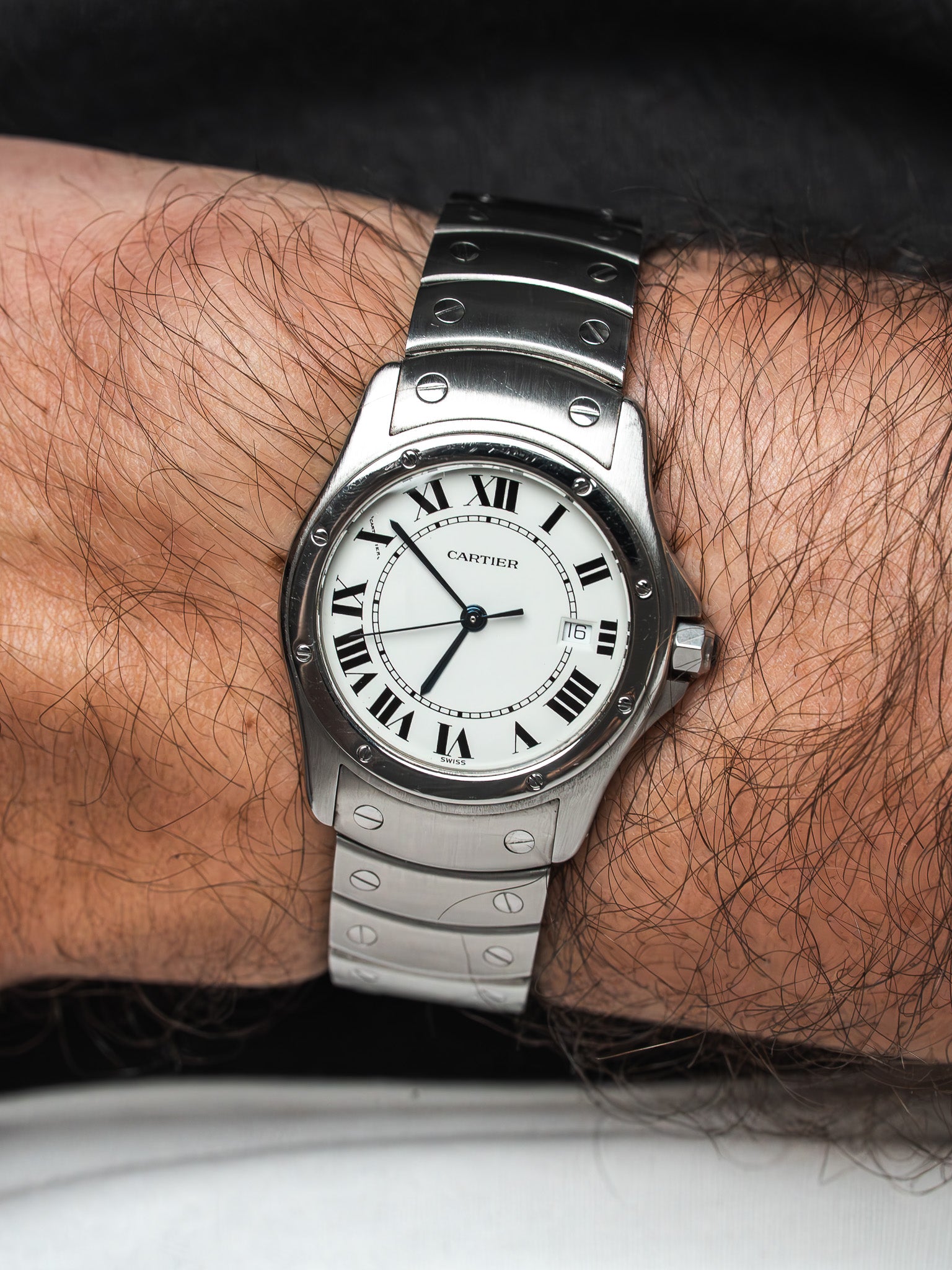 Cartier Santos watch with white dial, Roman numerals, steel bracelet on wrist