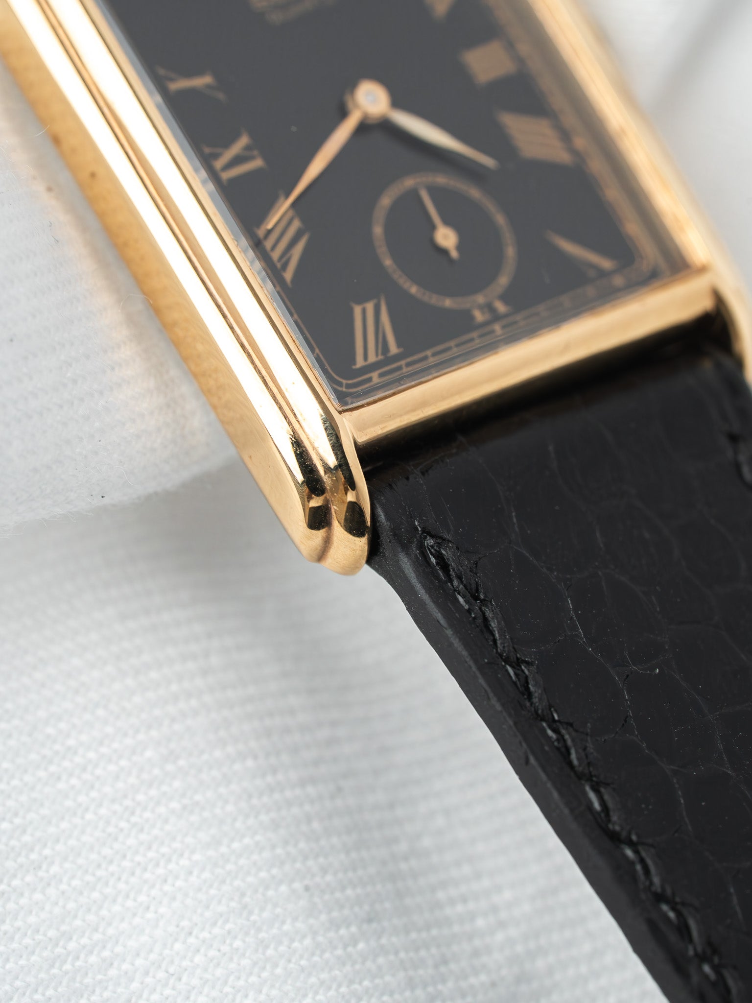 Cartier Tank vintage watch with gold case, black dial, and leather strap
