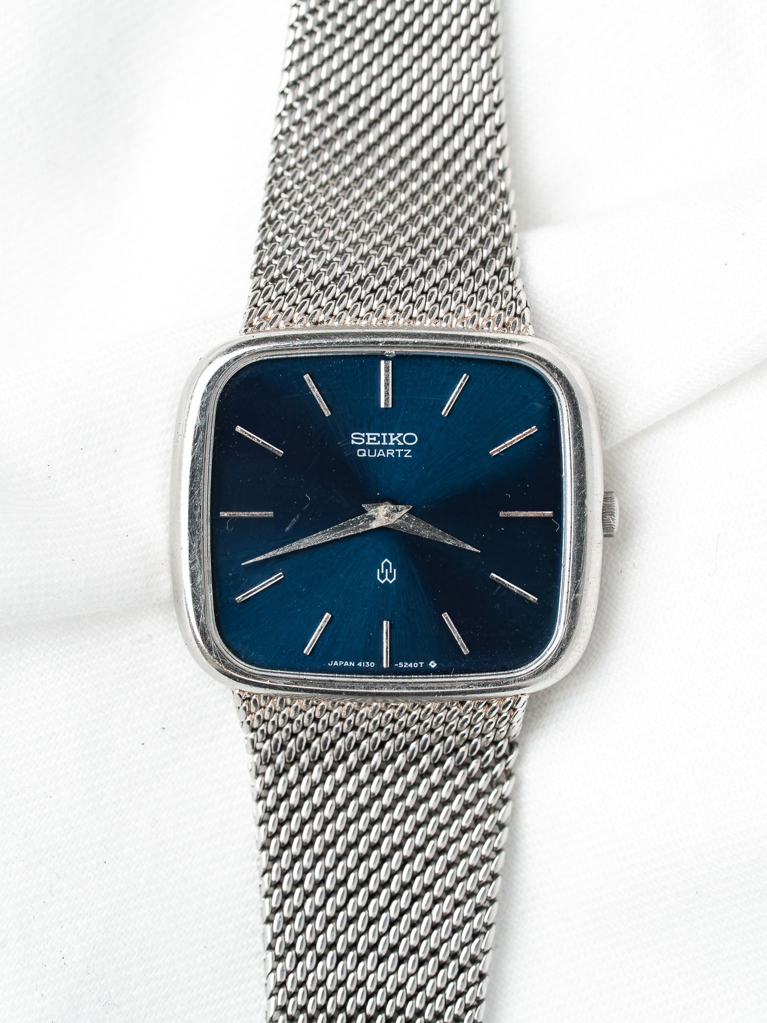 Vintage Seiko Quartz watch with blue dial, silver mesh bracelet, square case on white background