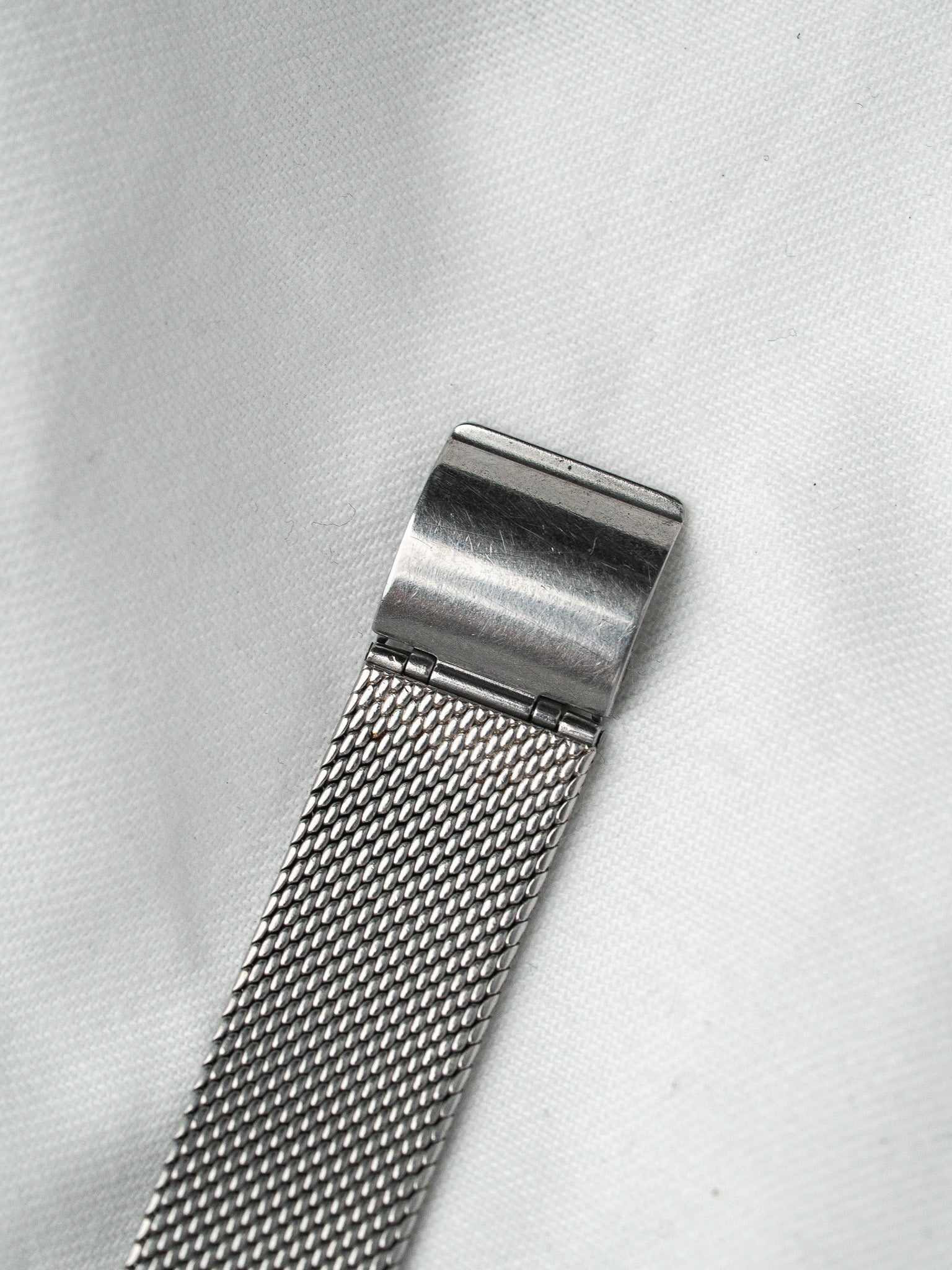 Vintage mesh bracelet with polished clasp, silver-toned metal on white fabric