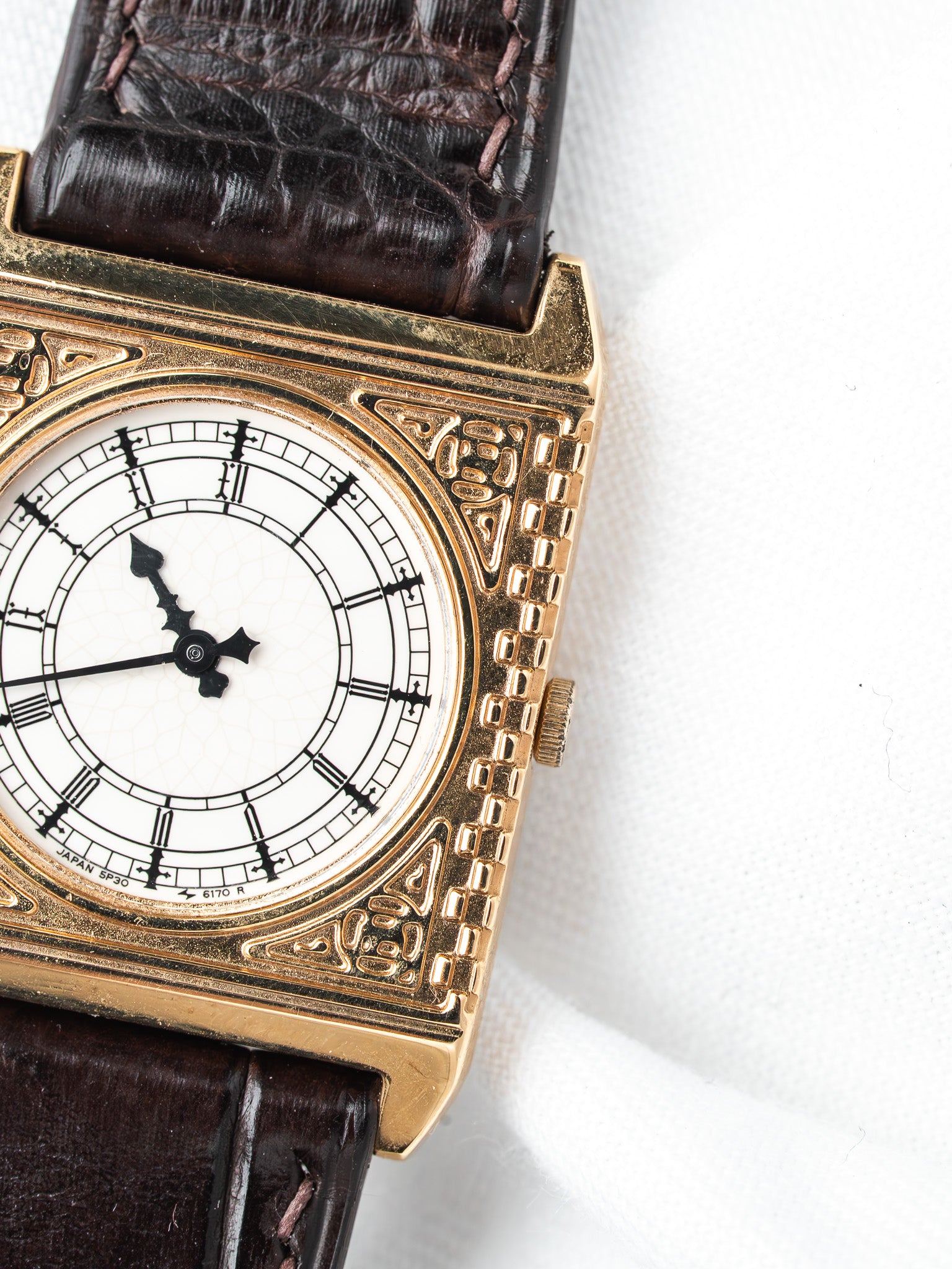 Vintage Seiko watch with gold case, white dial, Roman numerals, and brown leather strap