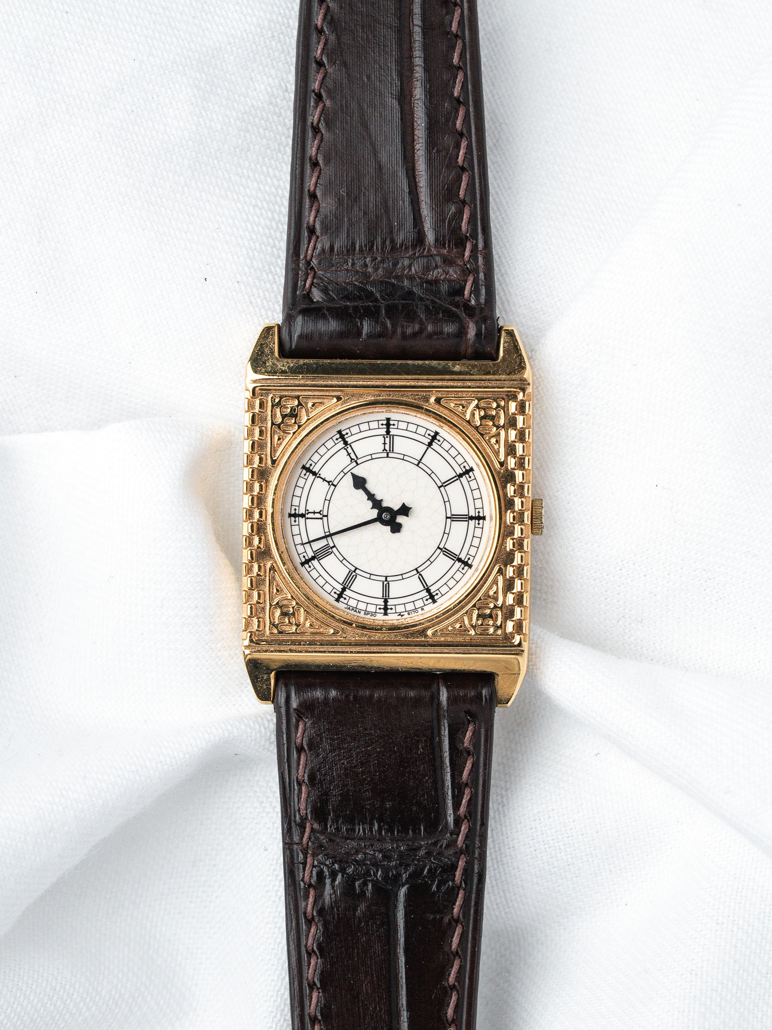 Vintage square gold watch with white dial, black hands, brown leather strap