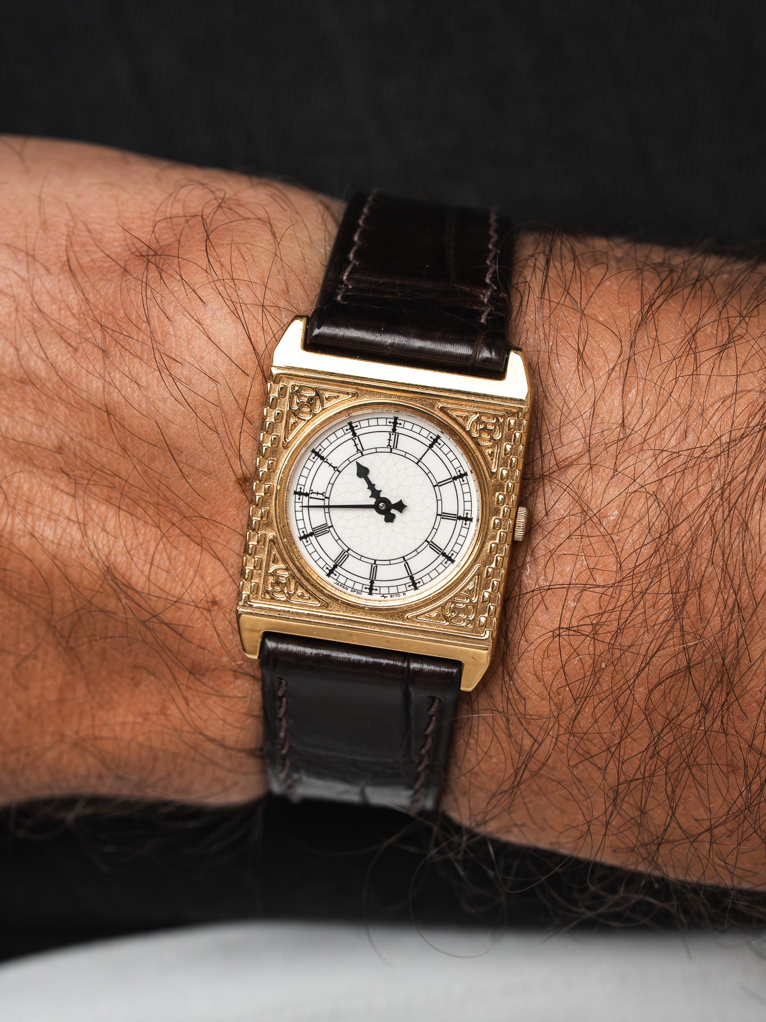 Vintage Seiko square gold case watch with white dial, Roman numerals, brown leather strap worn on wrist