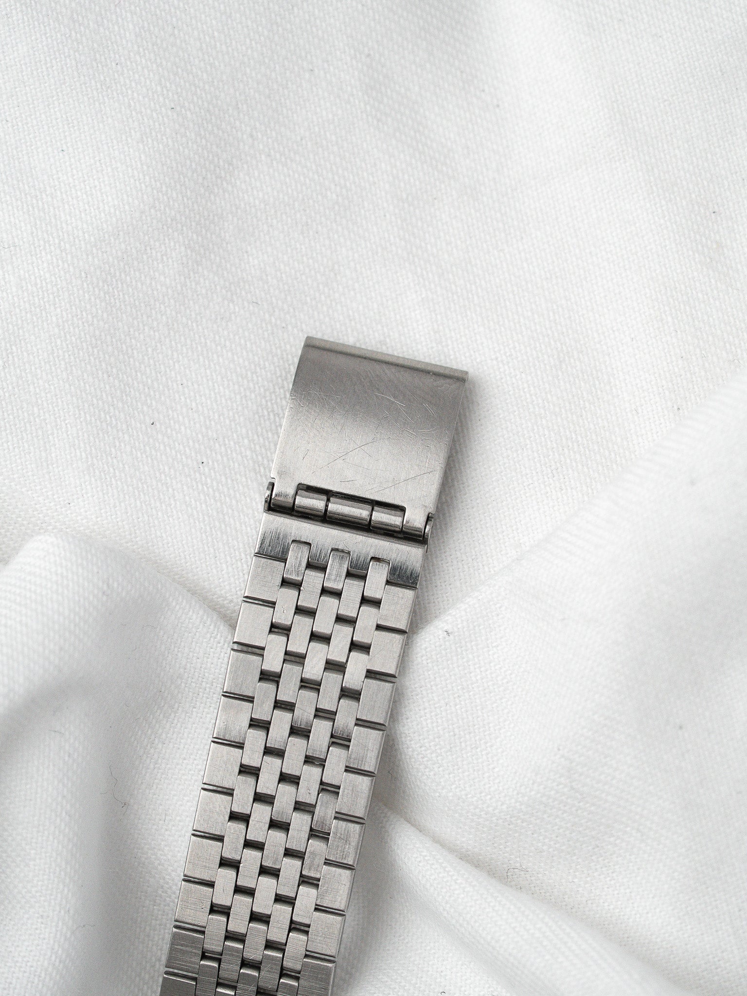 Vintage Rolex steel bracelet with woven link design on white fabric
