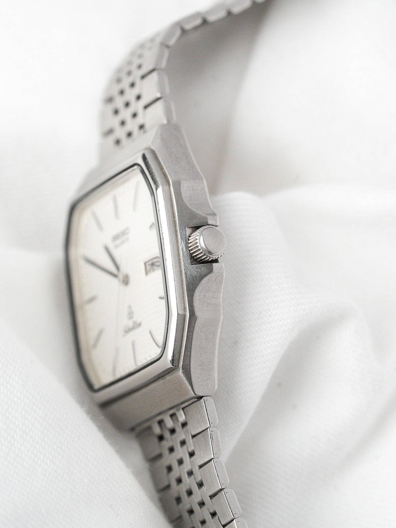Seiko vintage watch with white dial, steel case, and mesh bracelet on white background