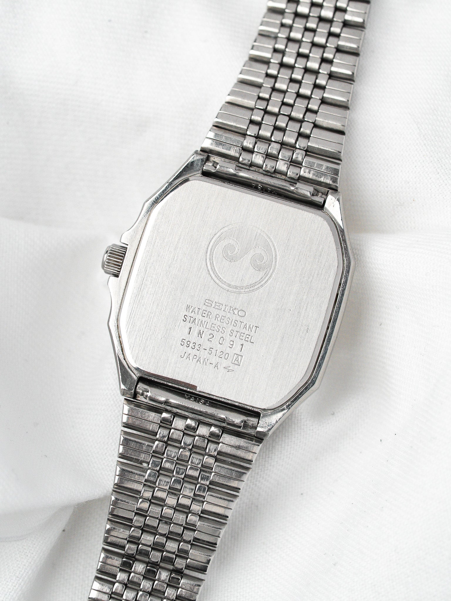 Seiko vintage watch with stainless steel case and mesh bracelet, back view on white background