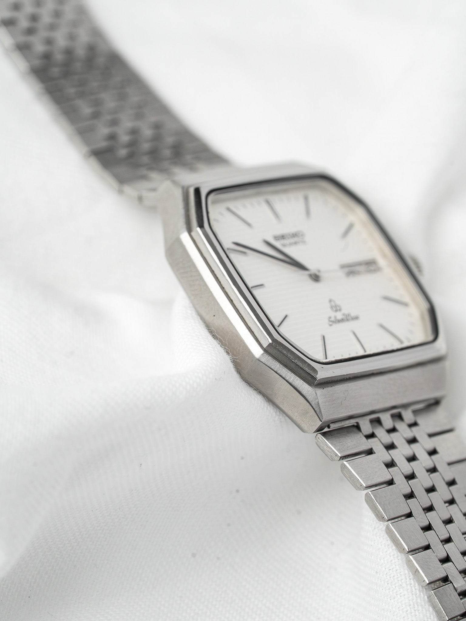 Seiko Silverwave vintage watch with silver dial, octagonal case, and metal bracelet on white fabric