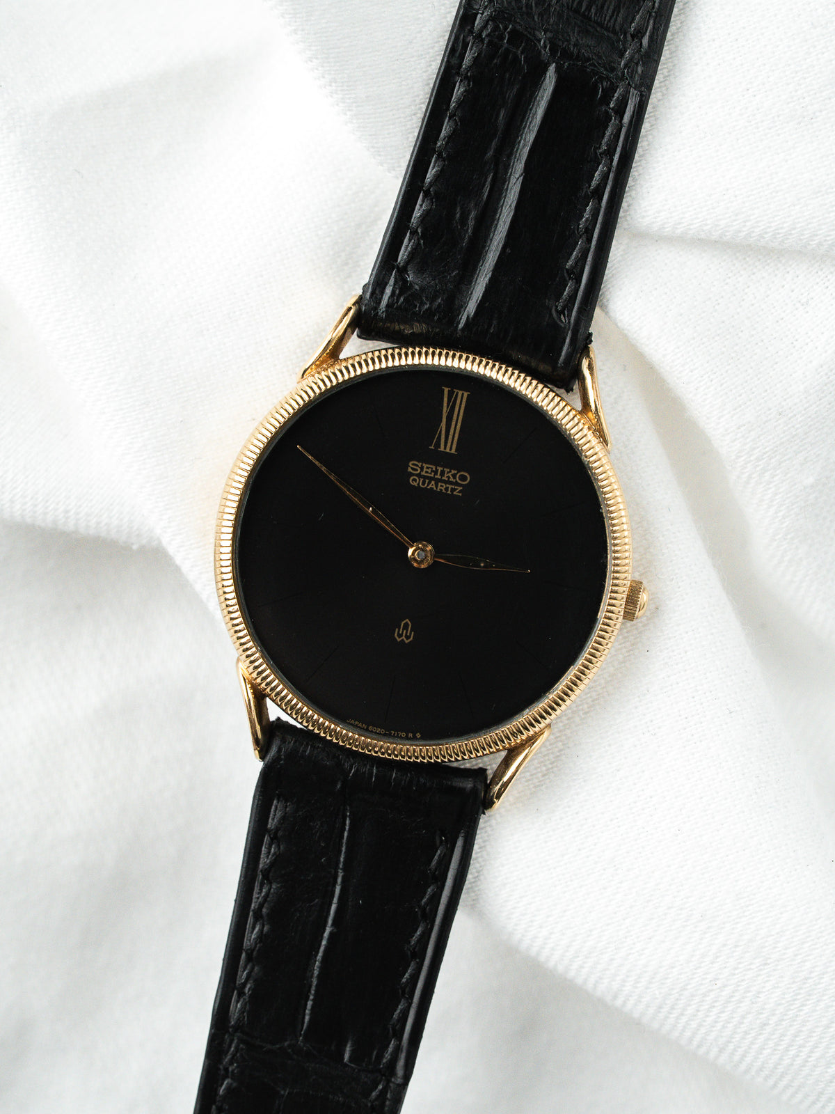 Montre Seiko Quartz vintage, boîtier doré, cadran noir et bracelet en cuir noir