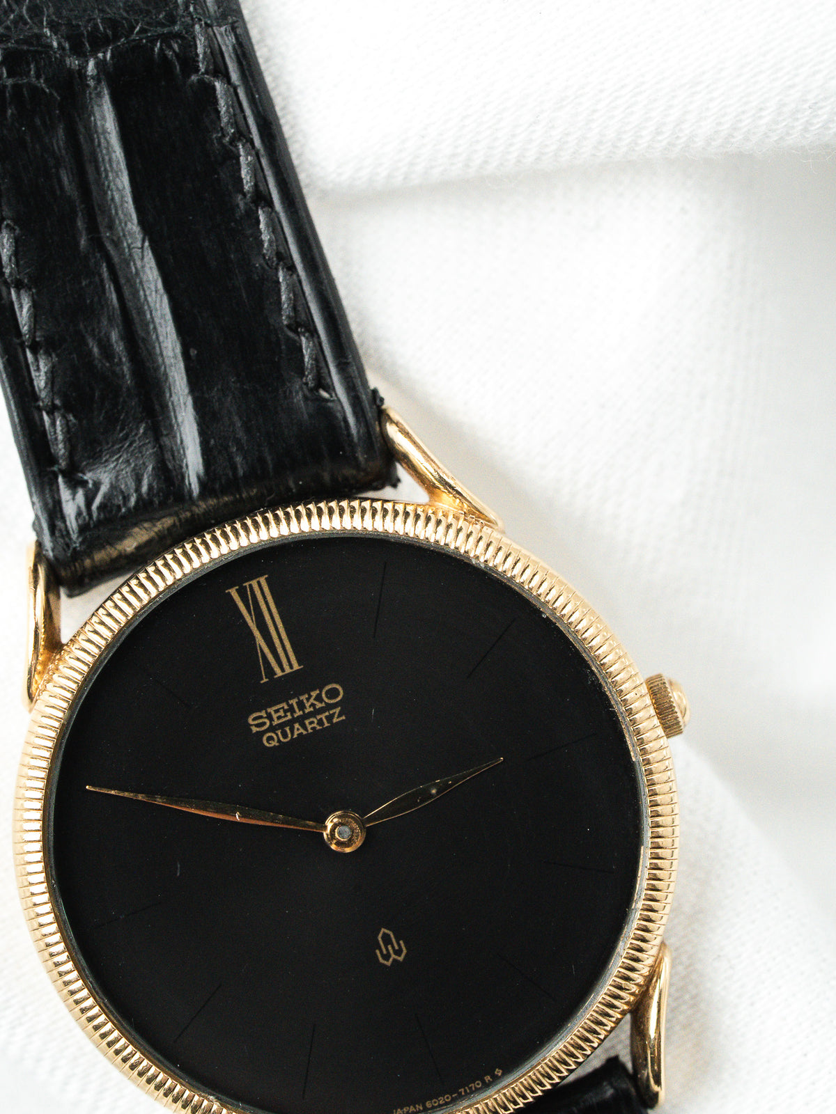 Montre Seiko Quartz vintage, boîtier doré, cadran noir et bracelet en cuir noir