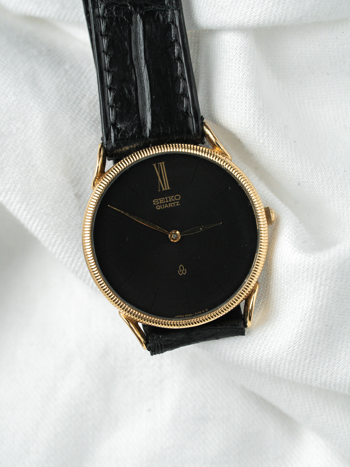 Montre Seiko Quartz vintage, boîtier doré, cadran noir et bracelet en cuir noir
