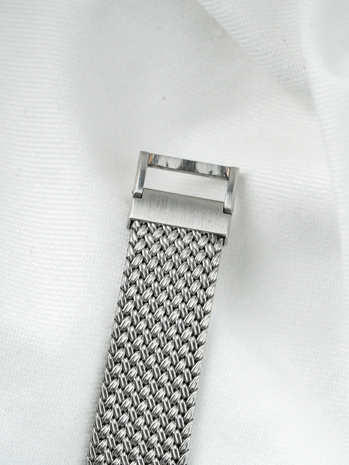 Bracelet de montre en maille milanaise argentée avec fermoir en acier sur fond blanc