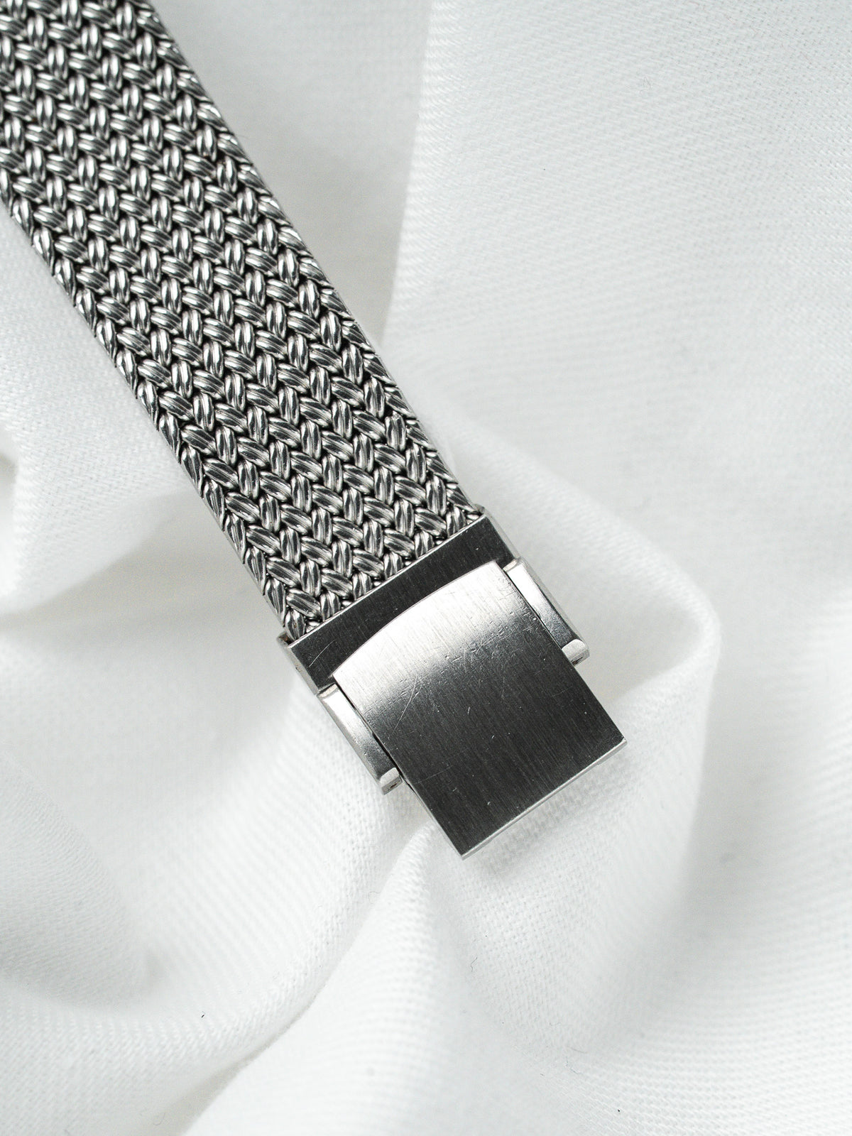 Bracelet de montre en maille milanaise en acier inoxydable sur fond blanc