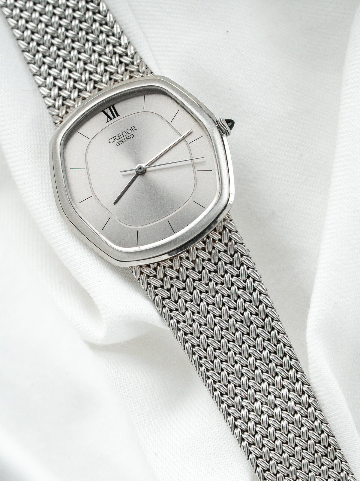 Montre Credor Seiko vintage en acier, boîtier carré et bracelet milanais sur fond blanc