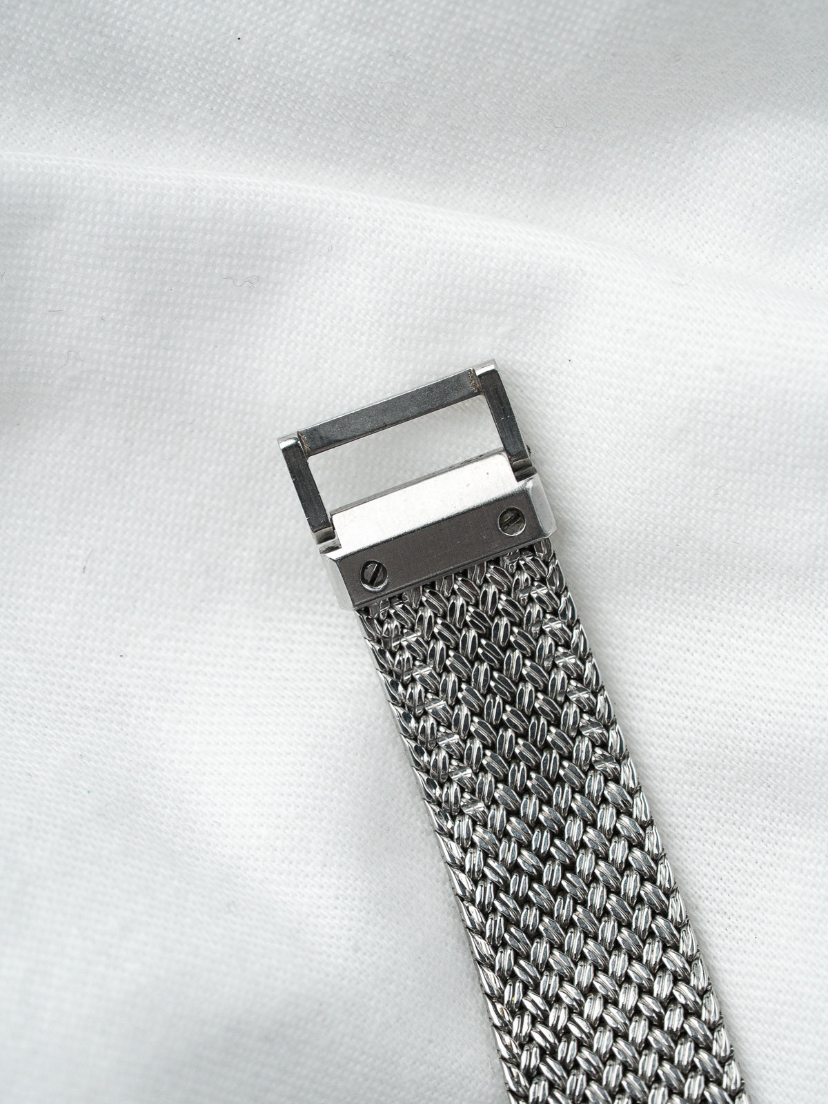 Bracelet de montre en maille milanaise en acier argenté sur fond blanc