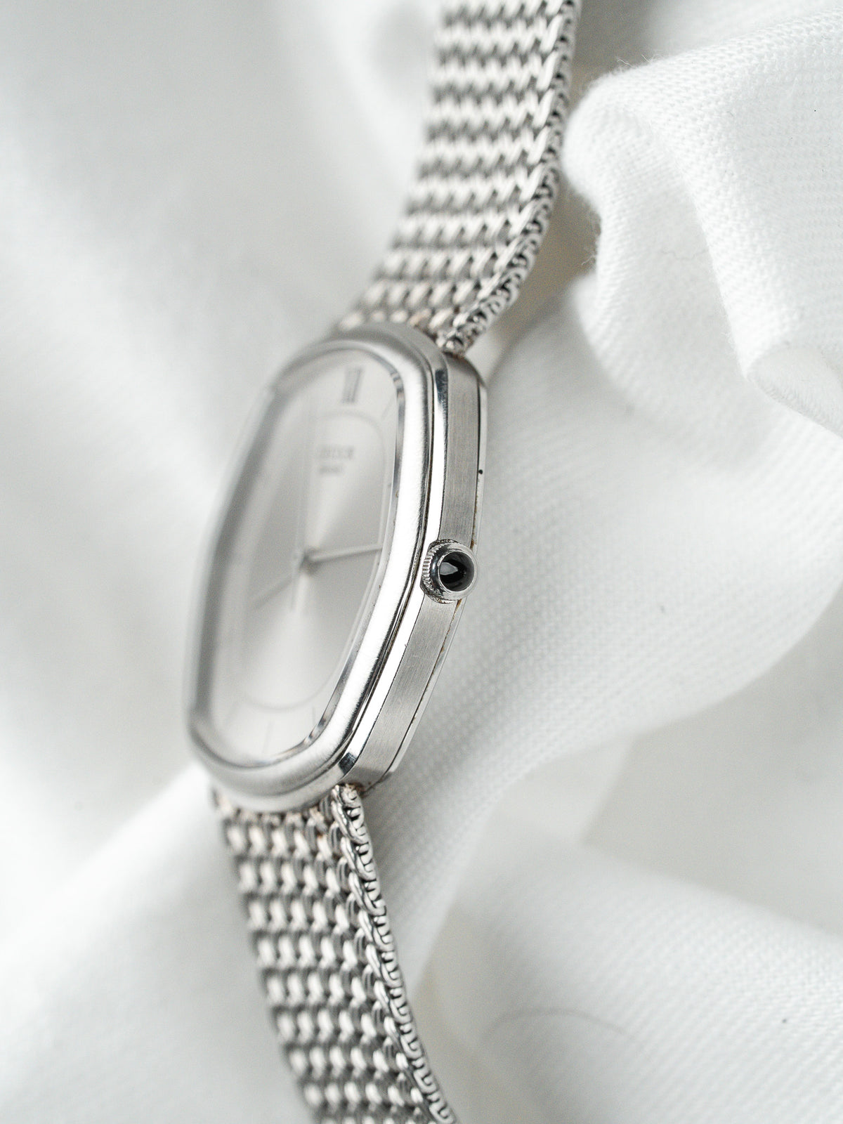 Montre vintage en acier au boîtier rectangulaire et bracelet maille milanaise sur fond blanc