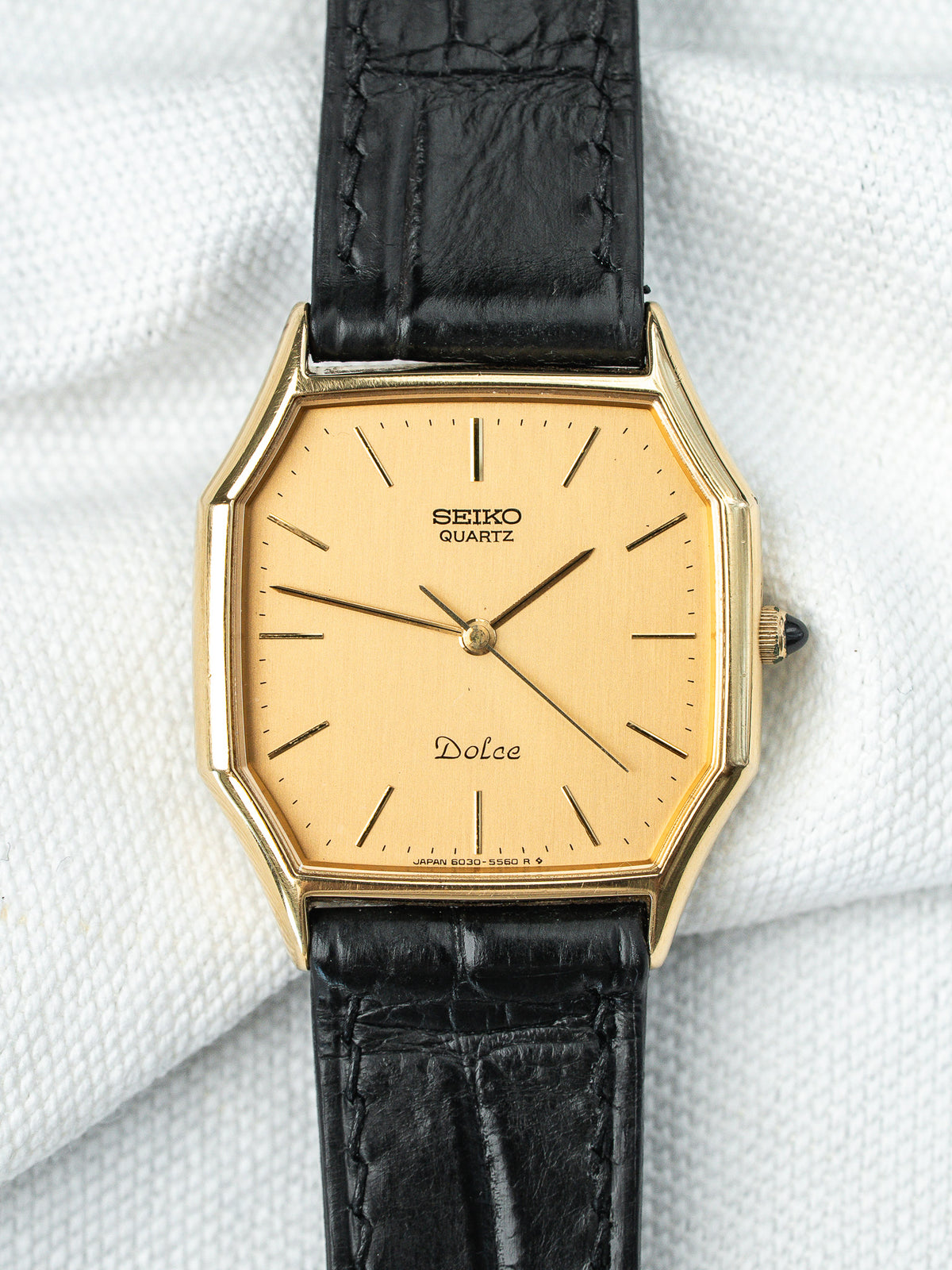 Montre Seiko Dolce vintage au boîtier doré octogonal et bracelet en cuir noir.