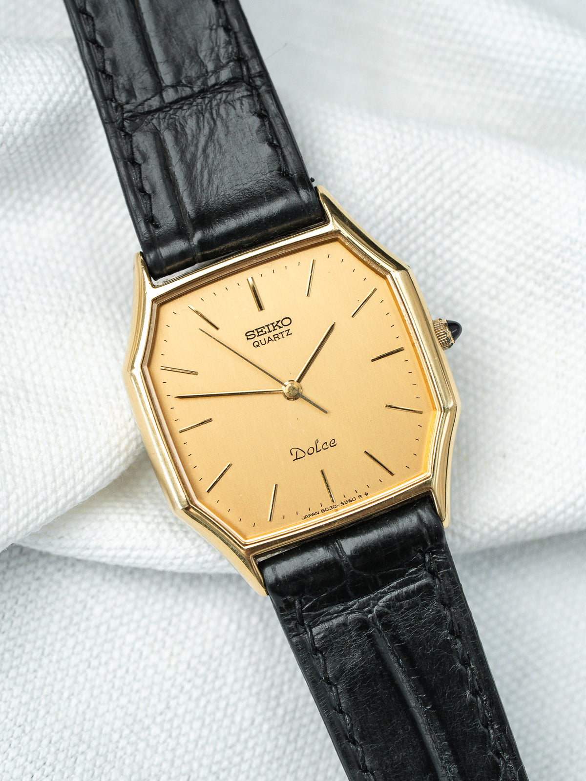 Montre Seiko Quartz Dolce vintage au boîtier doré octogonal et bracelet en cuir noir.