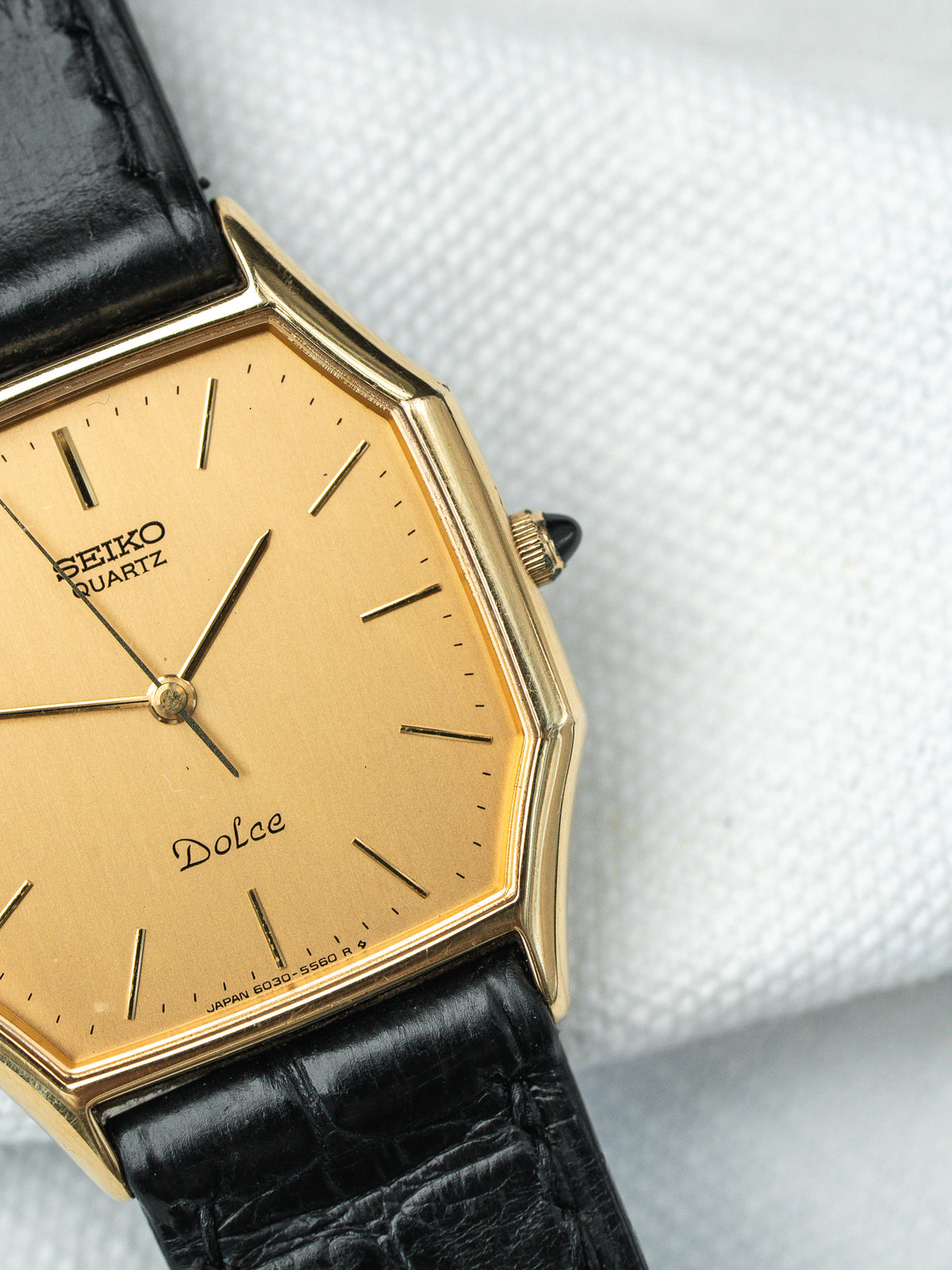 Montre Seiko Dolce vintage avec cadran doré et bracelet en cuir noir.