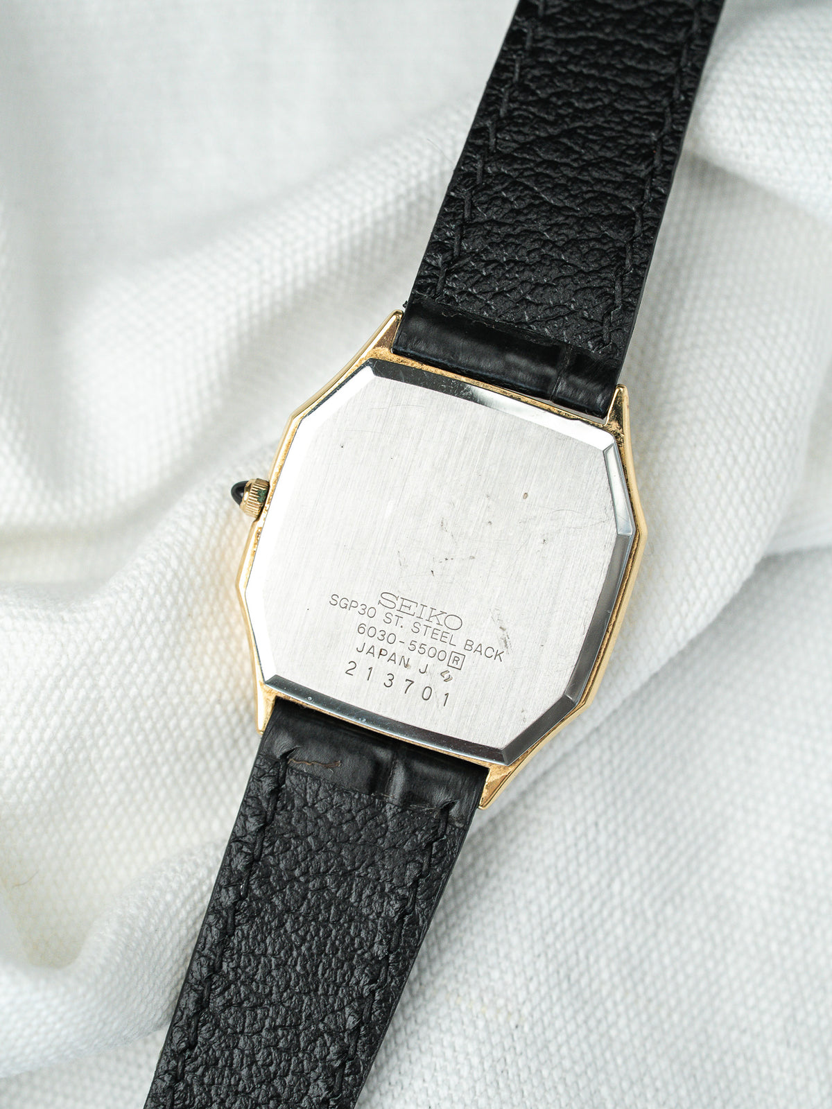 Dos en acier d'une montre Seiko avec bracelet en cuir noir grainé.