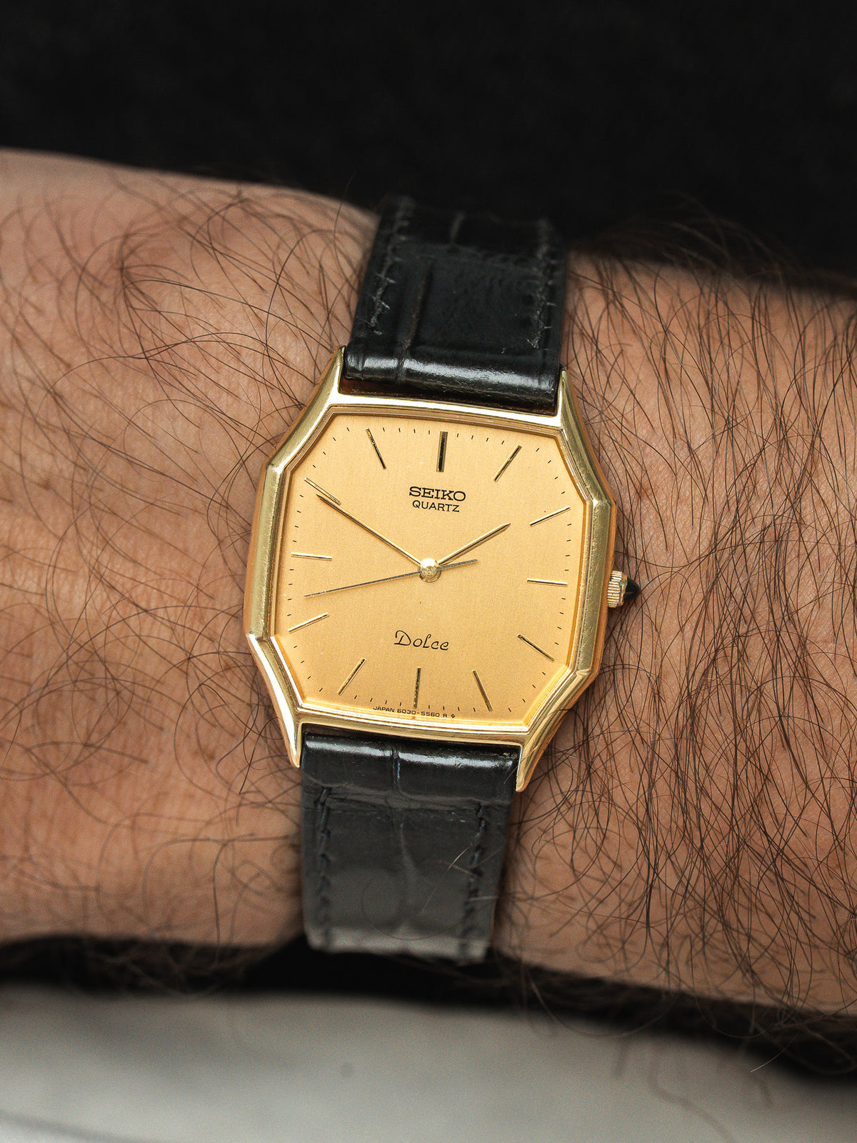 Montre Seiko Dolce vintage avec cadran doré octogonal et bracelet en cuir noir.
