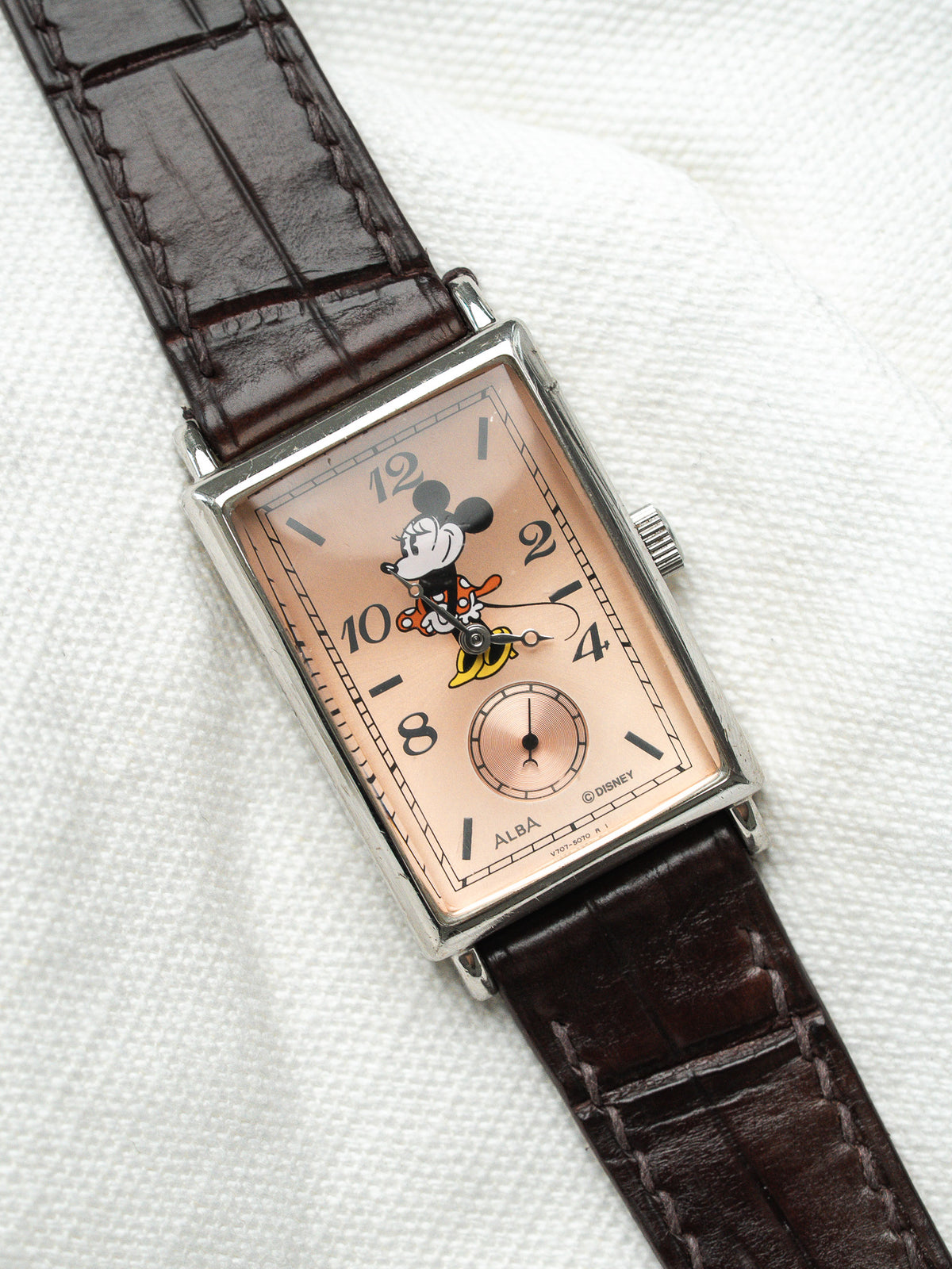 Montre Alba vintage rectangulaire au cadran rose avec Mickey Mouse et bracelet cuir marron.