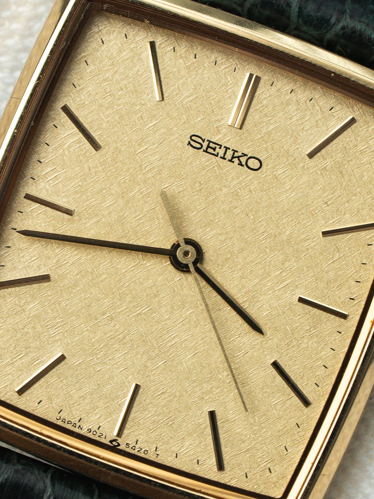 Gros plan sur le cadran doré texturé d'une montre vintage Seiko rectangulaire.