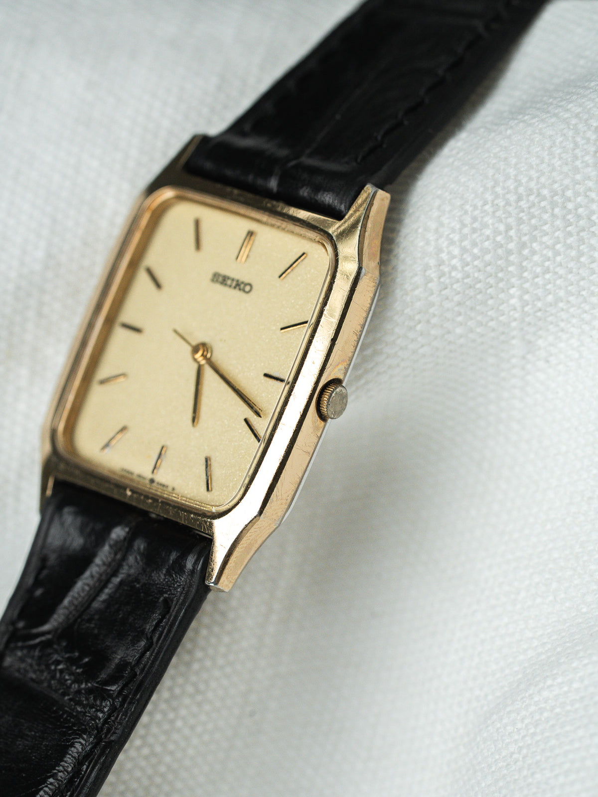 Montre Seiko vintage au boîtier rectangulaire doré avec bracelet en cuir noir