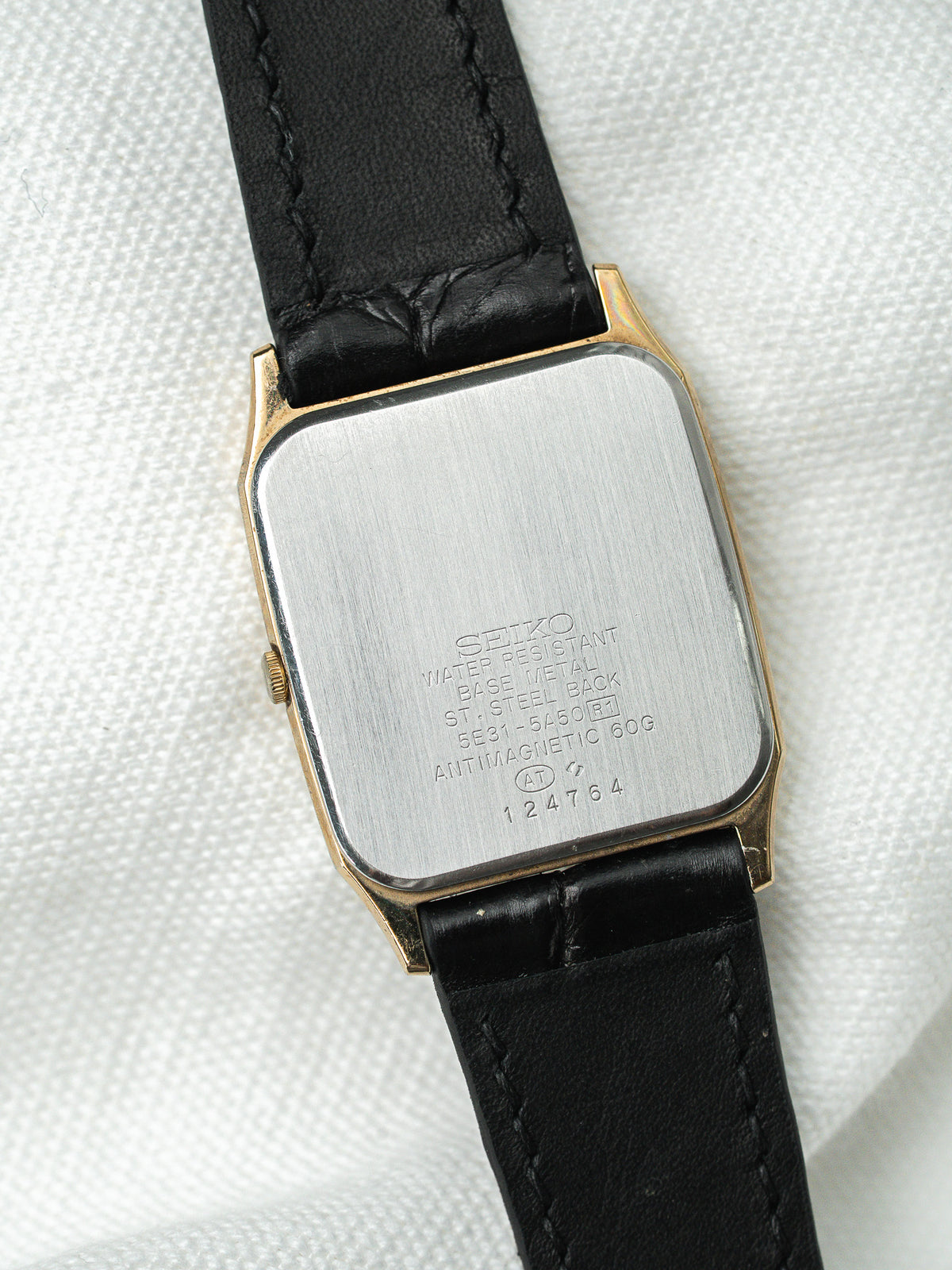 Dos en acier d'une montre rectangulaire vintage avec bracelet en cuir noir.