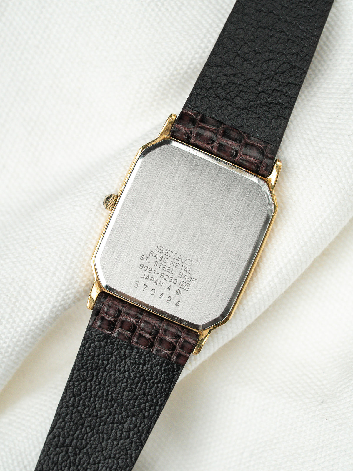 Dos en acier d'une montre Seiko vintage avec bracelet en cuir noir texturé.
