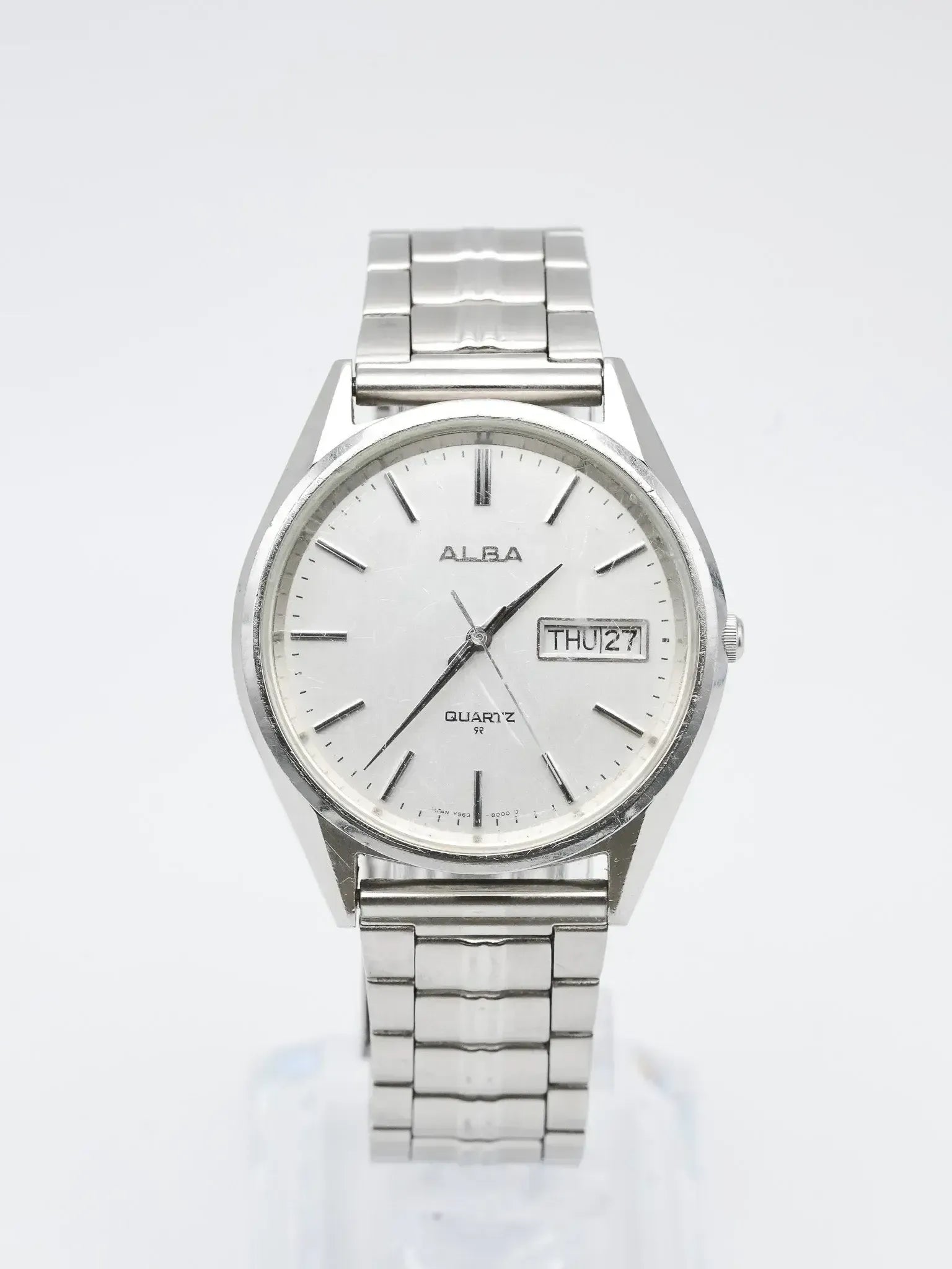 Alba vintage quartz watch with silver dial, day-date window, and steel bracelet on white background