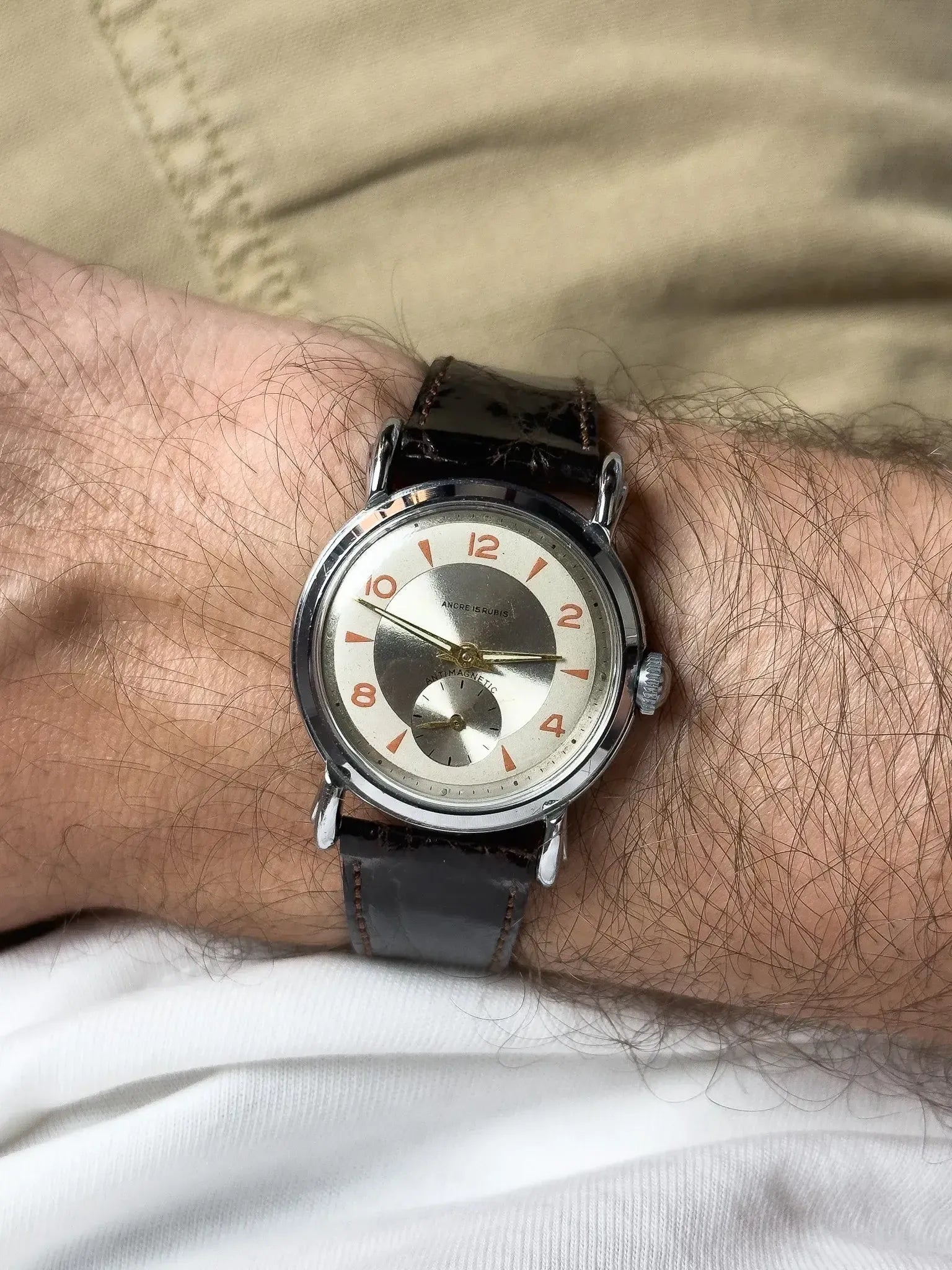 Vintage Andre 15 Rubis watch with silver dial, orange numerals, black leather strap on wrist