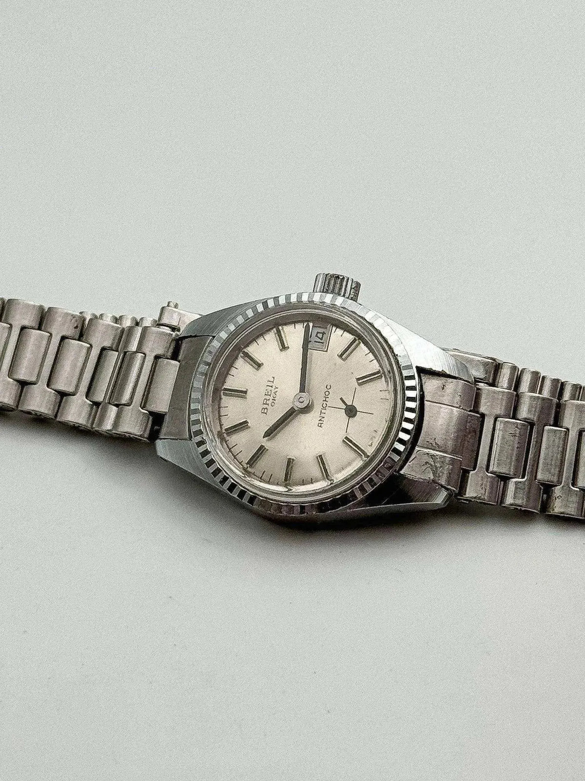 Vintage Breil Omay Antichoc watch with silver dial, steel bracelet, and textured bezel on neutral background