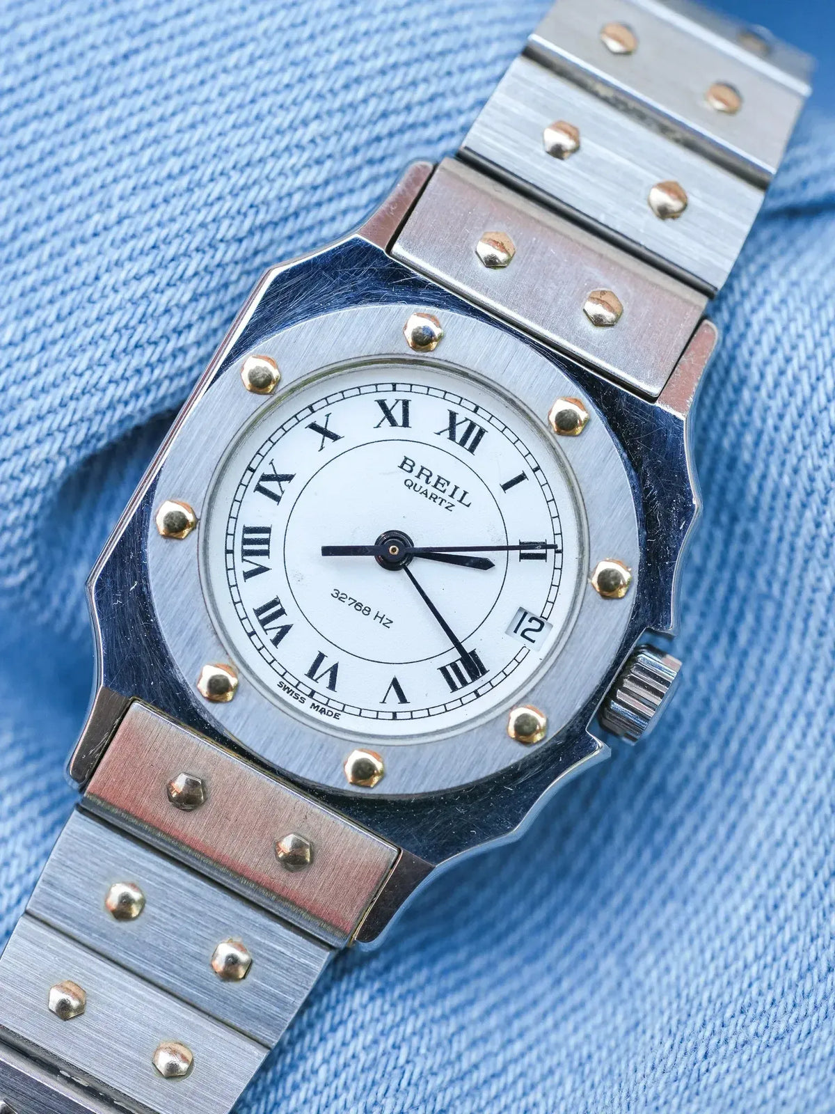 Breil quartz watch with white dial, Roman numerals, and two-tone metal bracelet on denim