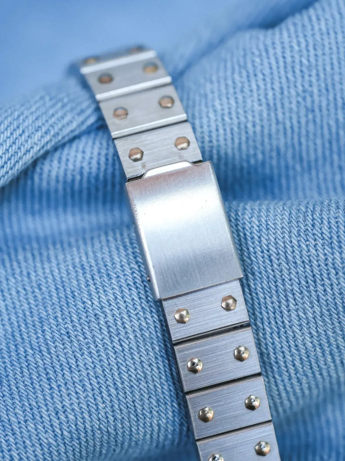 Vintage Rolex Oyster bracelet in brushed steel with gold screws on denim