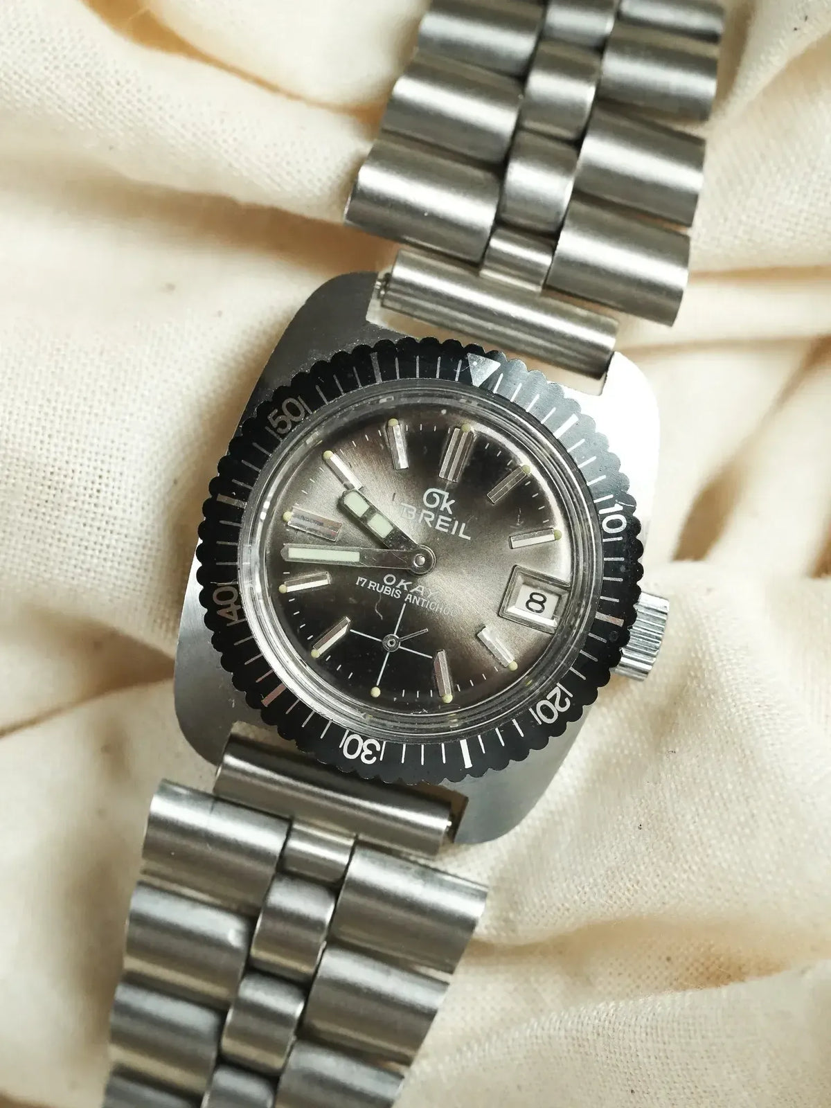 Vintage Doxa Sub 300T watch with black dial, steel bracelet, and rotating bezel on fabric